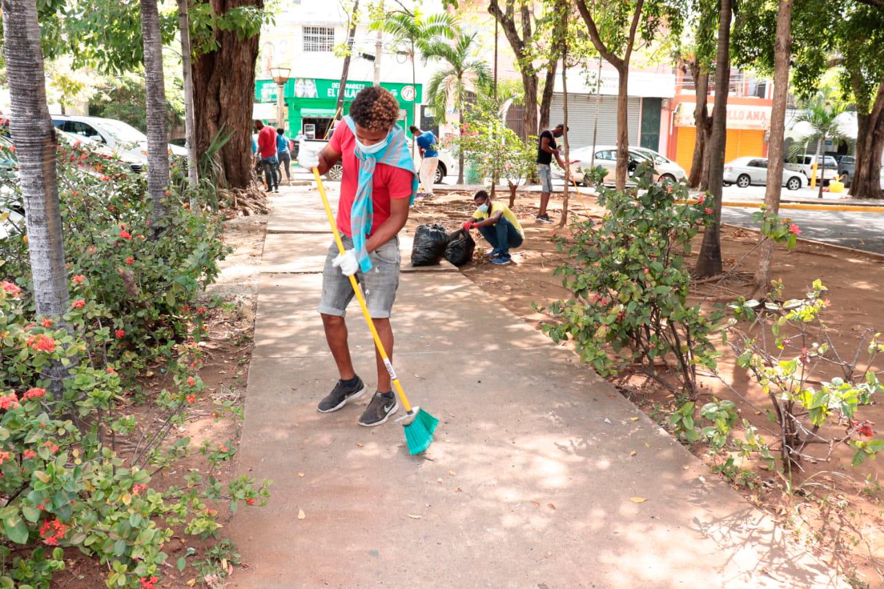 Uno de los sancionados por viola toque de queda barriendo en el parque María Eugenio de Hostos.  