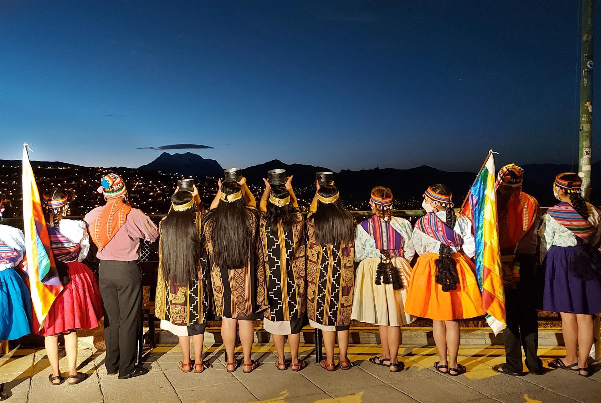 Jóvenes disfrazados de indígenas se preparan este lunes en el mirador de Killi Killi para participar en el acto del recibimiento del 5529 nuevo Año Andino Amazónico y del Chaco, en la ciudad de La Paz. Los bolivianos recibieron este lunes los primeros rayos del sol con las palmas en alto para celebrar el Año Nuevo Andino número 5529, en medio de rituales ancestrales llevados a cabo en diversos sitios considerados sagrados para los indígenas. EFE/Laura Núñez