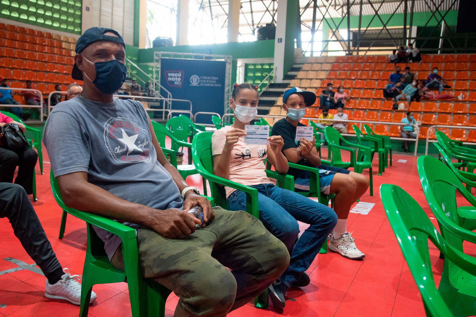 Un padre acompaña a sus hijos a recibir la segunda dosis de Pfizer, el 4 de julio de 2021.