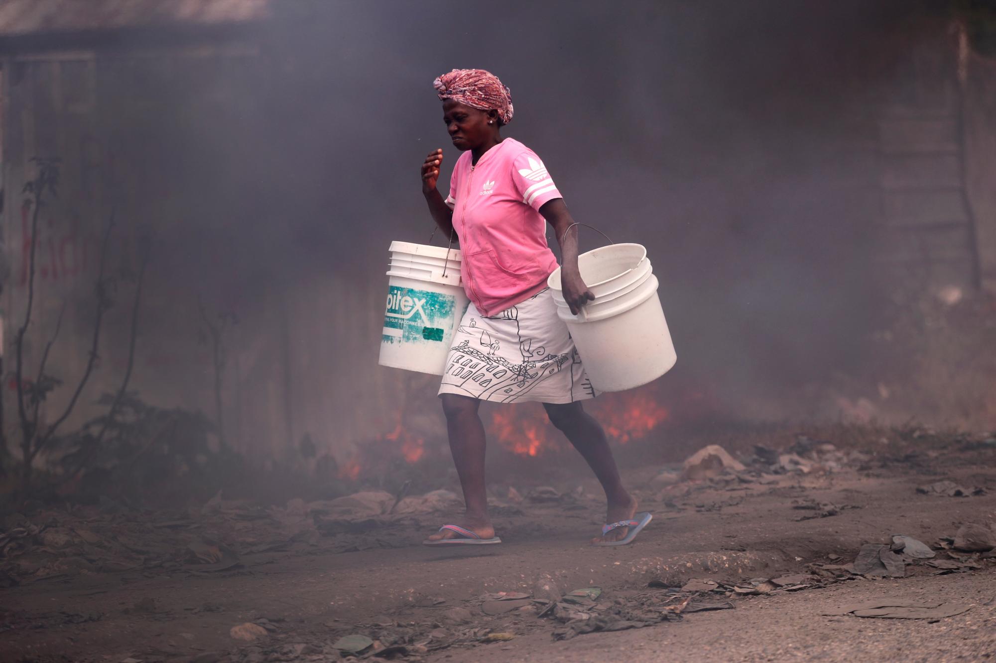 PUERTO PRÍNCIPE (HAITÍ), 11/02/2021.- Una mujer camina hoy junto a unas barricadas en llamas, durante una protesta contra el Gobierno en Puerto Príncipe (Haití). Haití sufre por estos días una nueva crisis política tras la jubilación forzosa de tres jueces opositores ordenada el lunes por el Gobierno de Jovenel Moise, en aparente violación de la Constitución. EFE/ Orlando Barría