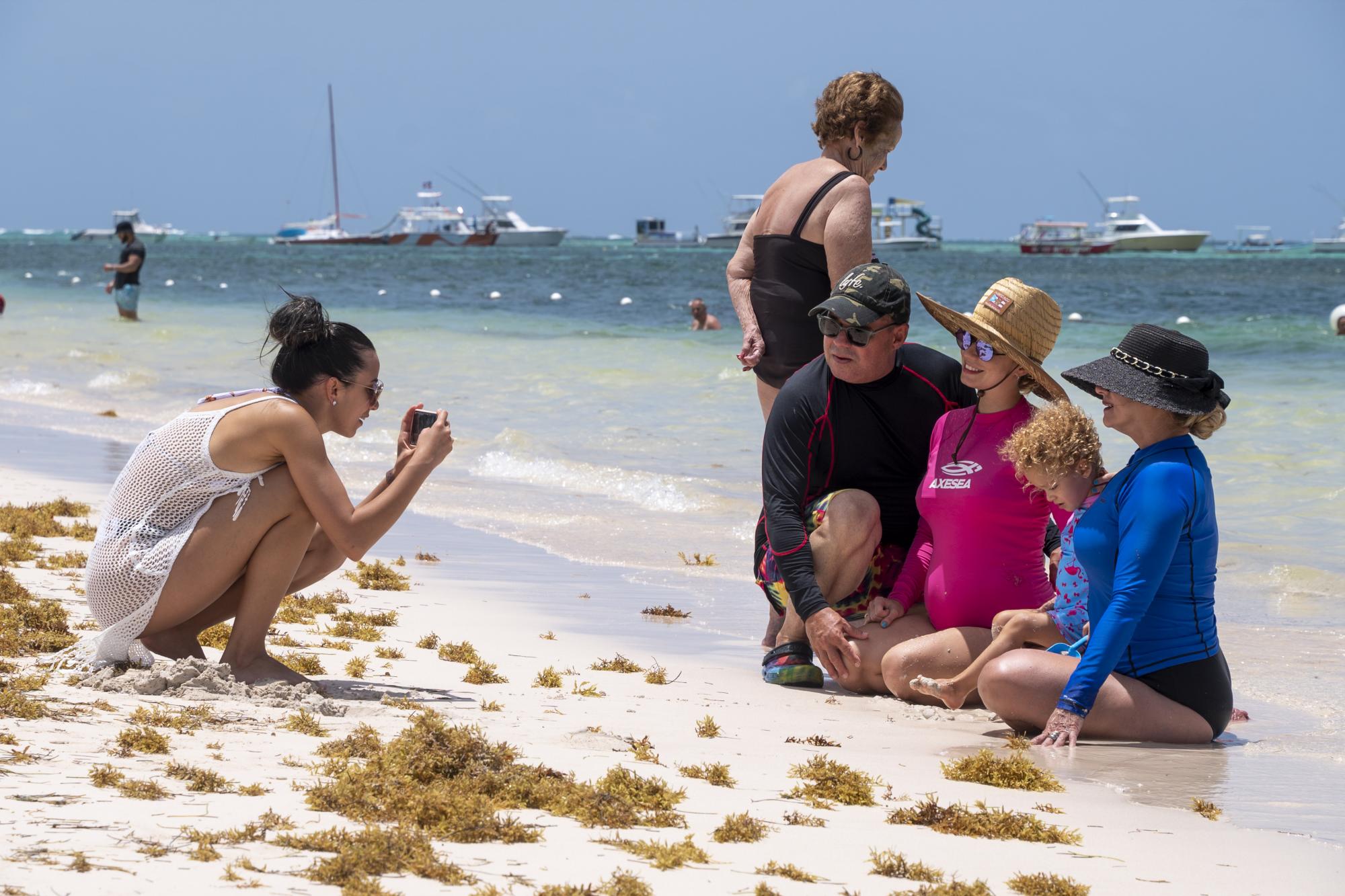 Una familia se toma una foto, rodeados de sargazo, en la playa Bibijagua, en Bávaro, provincia La Altagracia (Foto: Nelson Pulido)