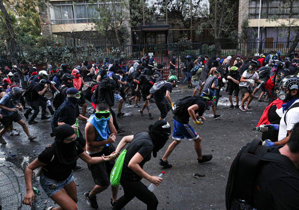 En esta foto del 6 de marzo de 2020, manifestantes corren durante enfrentamientos con la policía en Santiago, Chile.