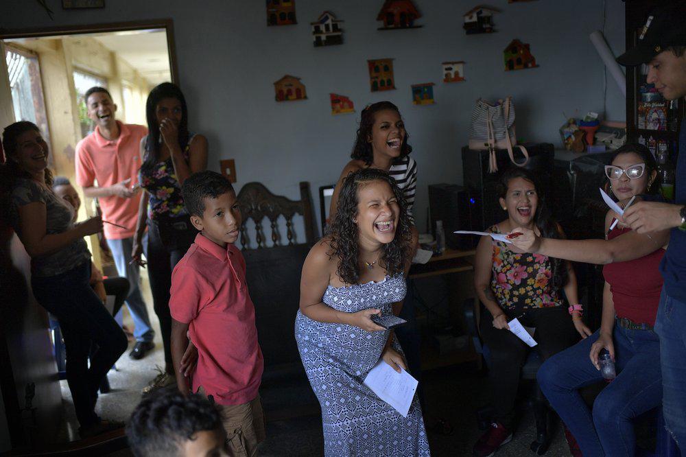 Ada Mendoza, de 24 años, sonríe durante un juego de acertijos durante su baby shower en el apartamento de sus padres en el barrio Catia de Caracas, Venezuela, el sábado 5 de septiembre de 2020. (AP Foto/Matias Delacroix)