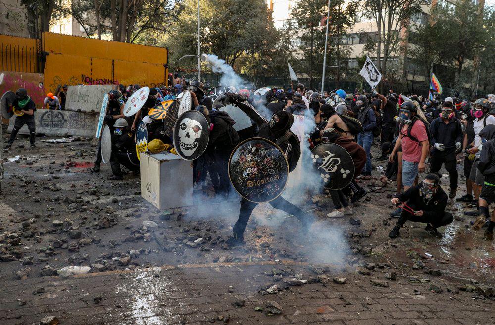 En esta foto del 6 de marzo de 2020, un manifestante antigubernamental devuelve un bote de gas lacrimógeno a la policía durante enfrentamientos en Santiago, Chile.