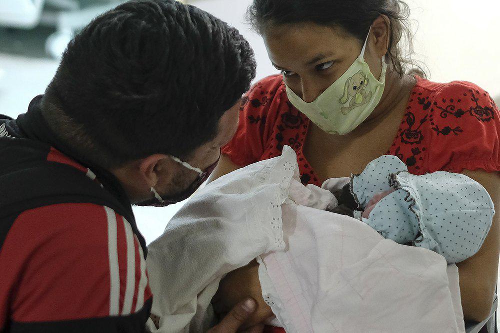 Ada Mendoza, de 24 años, muestra a su hija Peyton a su pareja Leo Camejo por primera vez, horas después de dar a luz en el Hospital Público de Maternidad y Niños Hugo Chávez Frías, en el barrio El Valle de Caracas, Venezuela, el jueves 10 de septiembre de 2020. (AP Foto/Matias Delacroix)