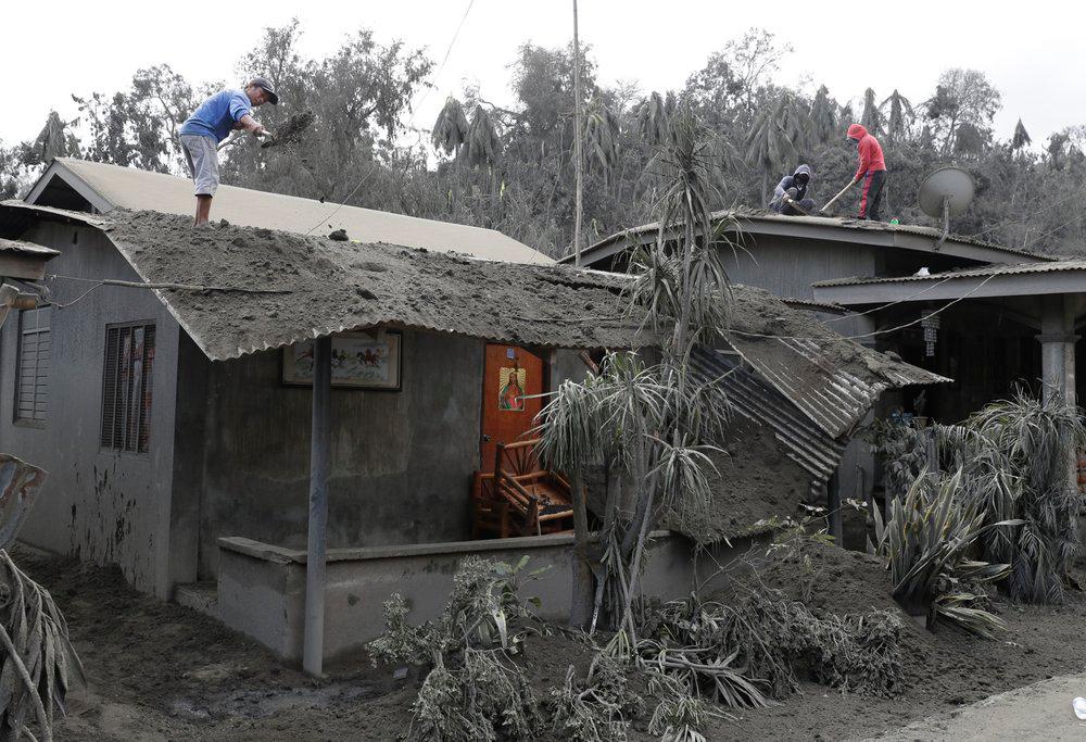Tres lugareños limpian las cenizas del techo de una casa en Laurel, al sur de las Filipinas, tras la erupción de un volcán el 14 de enero del 2020. 