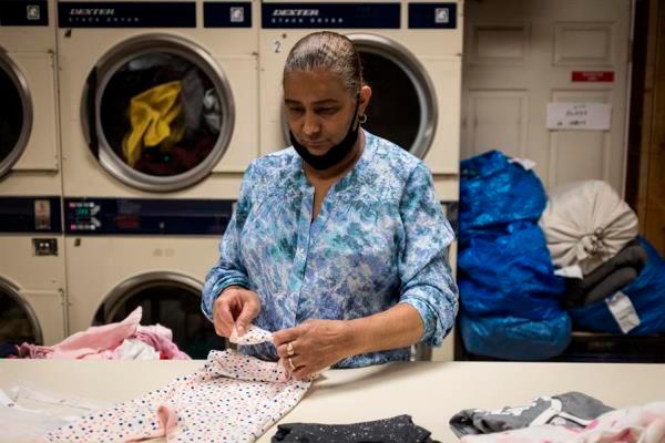 Nancy Cruz, de 55 años y originaria de República Dominicana, mientras dobla ropa en ‘Graham Laundromat’, el negocio familiar en el que trabaja en Brooklyn, Nueva York (EE.UU.). 