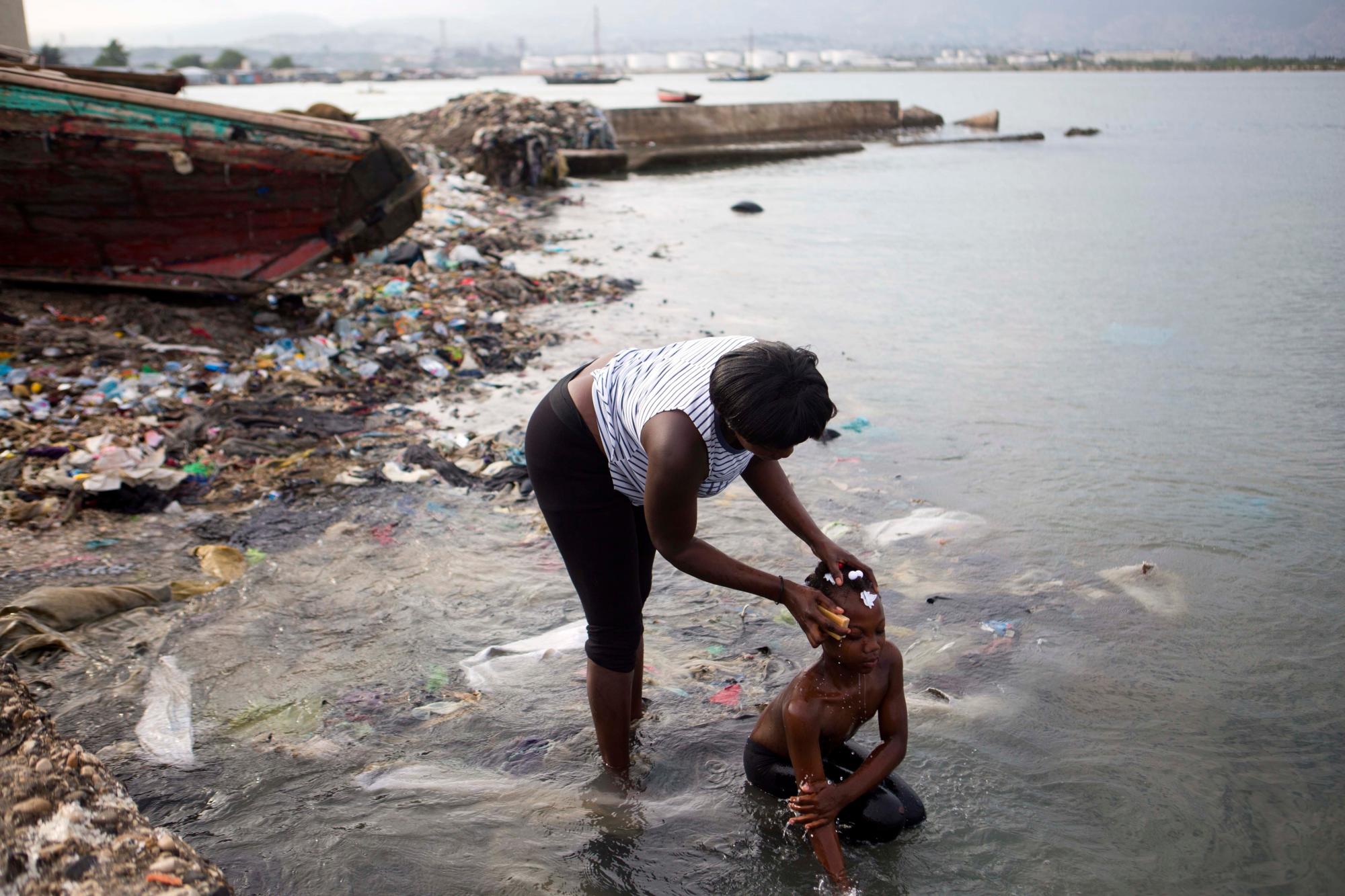 En imagen del domingo 17 de marzo de 2019, una mujer baña a su hija mientras se preparan para acudir a la iglesia, en la comunidad de Cité Soleil, en Puerto Príncipe, Haití.