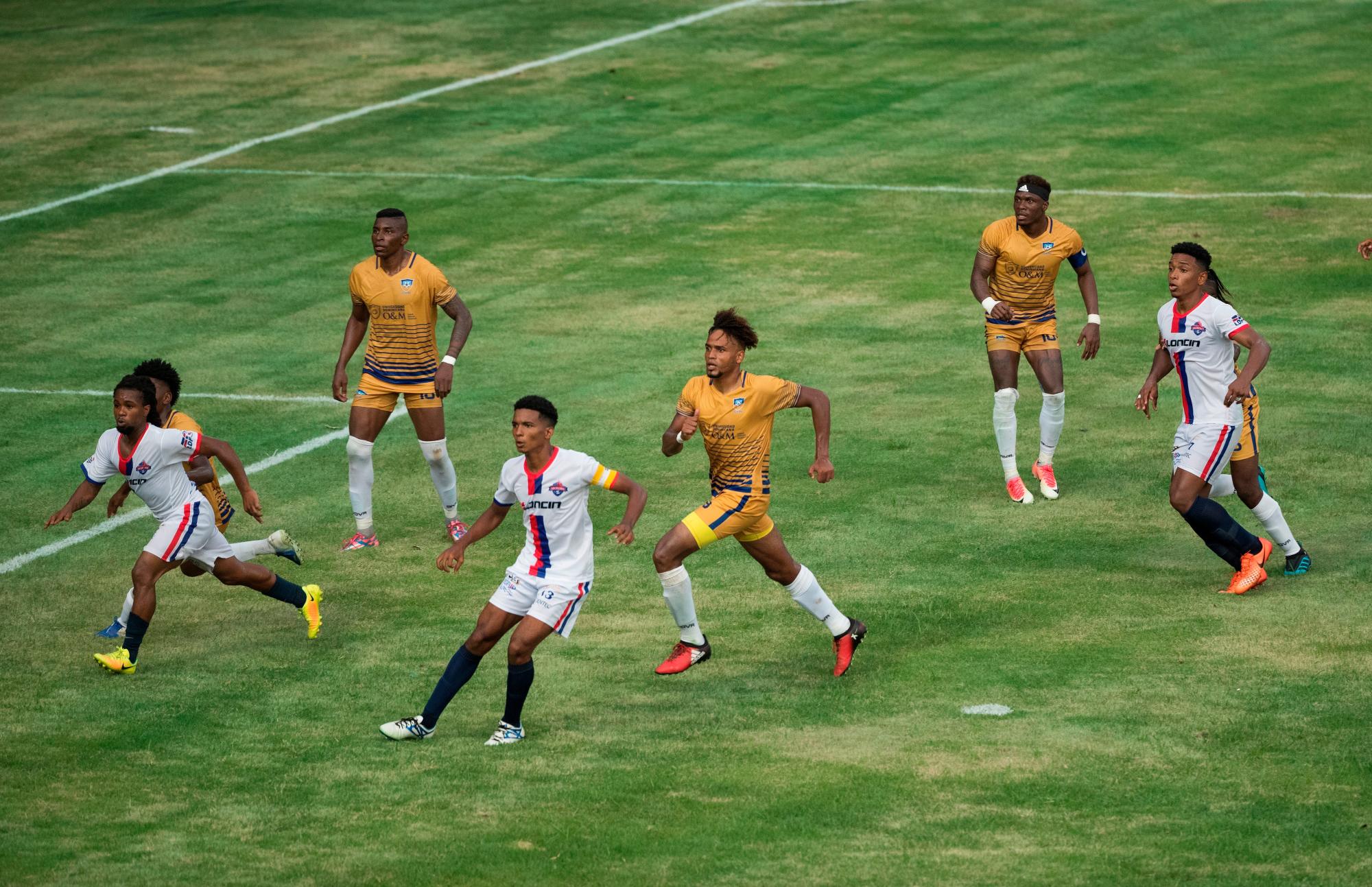 Jugadores de la Universidad O&M y Atlético San Cristóbal disputan un balón hoy durante el partido inicial de la Liga Dominicana de Fútbol, en San Cristóbal (República Dominicana).