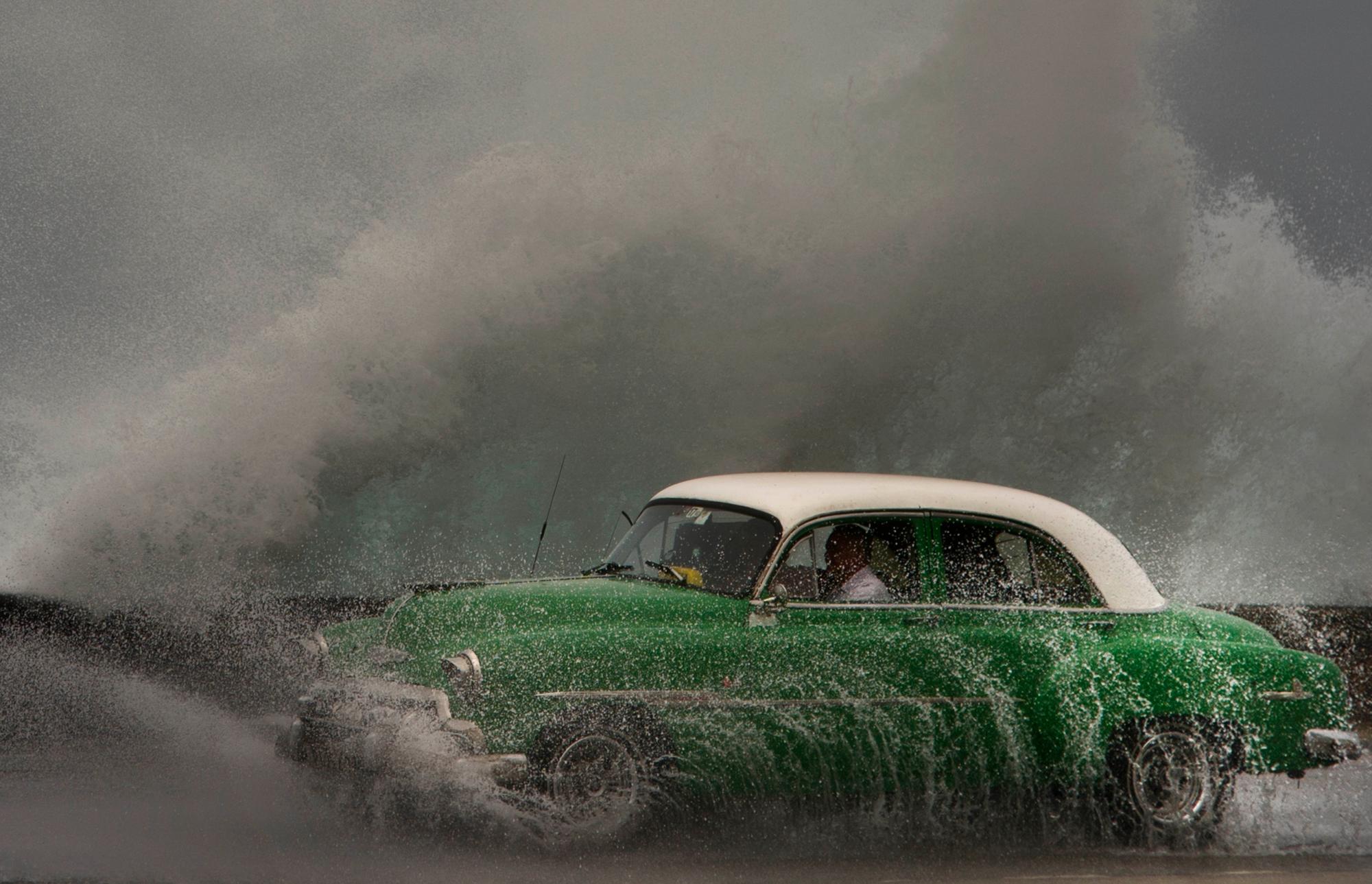 En imagen del martes 19 de marzo de 2019, las olas se estrellan contra el muro del Malecón mientras un taxi cruza en La Habana, Cuba. 