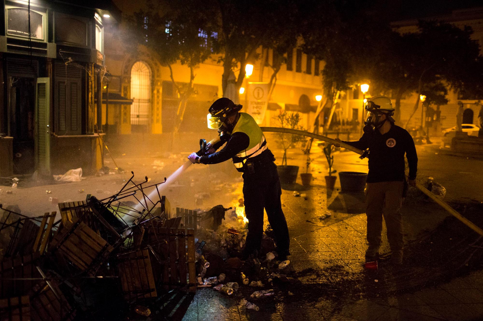 Los bomberos apagaron el incendio de los muebles urbanos quemados después de los choques, exigiendo la renuncia del gobernador Ricardo Rossello, en San Juan, Puerto Rico, el jueves 18 de julio de 2019.