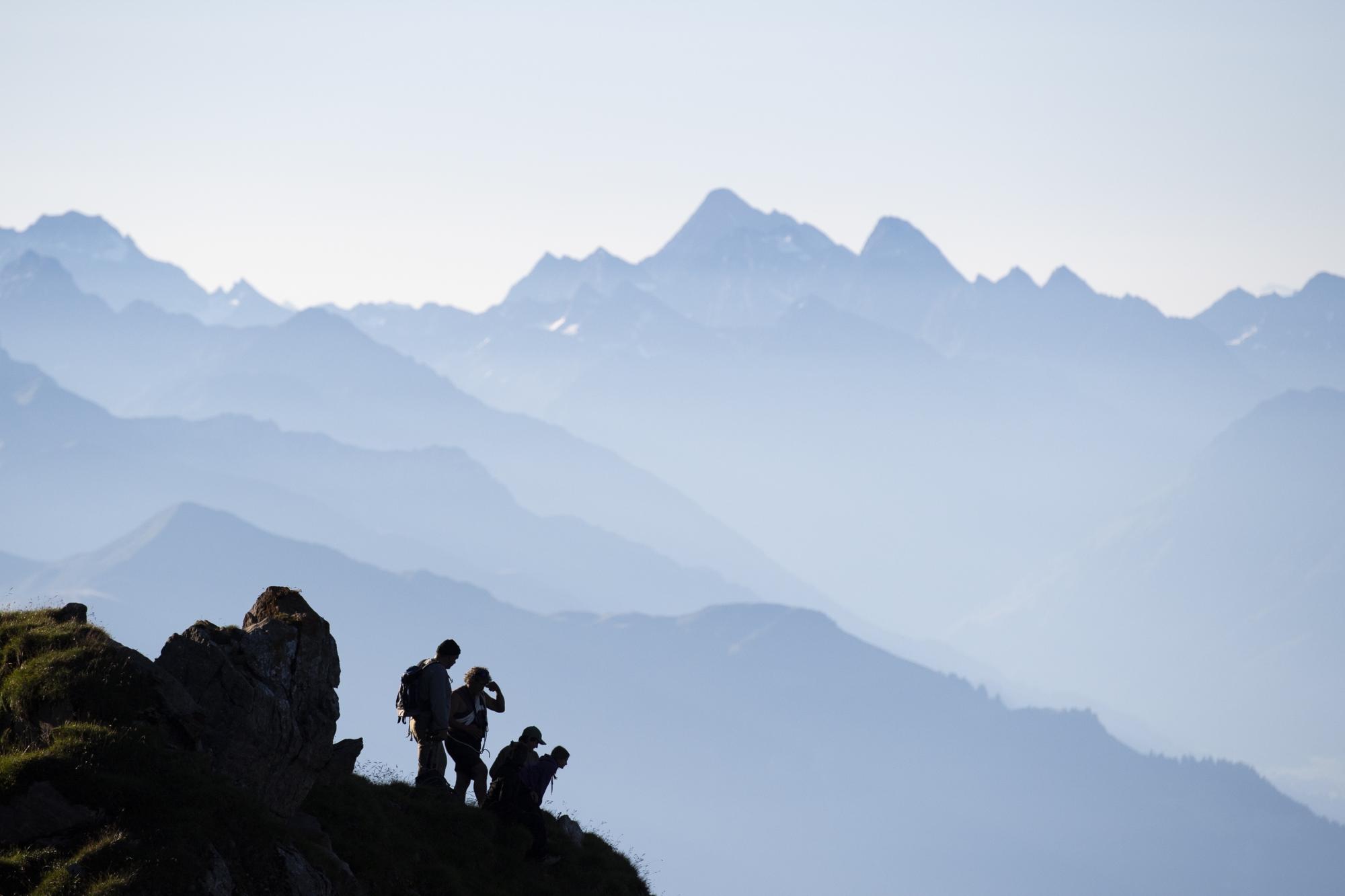 Los excursionistas observan cómo un rebaño de ovejas cruza un terreno alpino bajo pico Falknis (2.562 m), en Flaesch, Suiza, este viernes 7 de agosto. EFE/GIAN EHRENZELLER