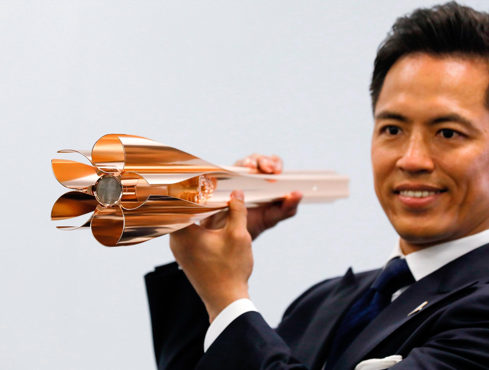 Tadahiro Nomura (c), tricampeón olímpico de judo, exhibe la antorcha olímpica de los Juegos de Tokio 2020 durante la ceremonia de presentación este miércoles en Tokio (Japón), un año antes de la llegada de la llama olímpica al país. 