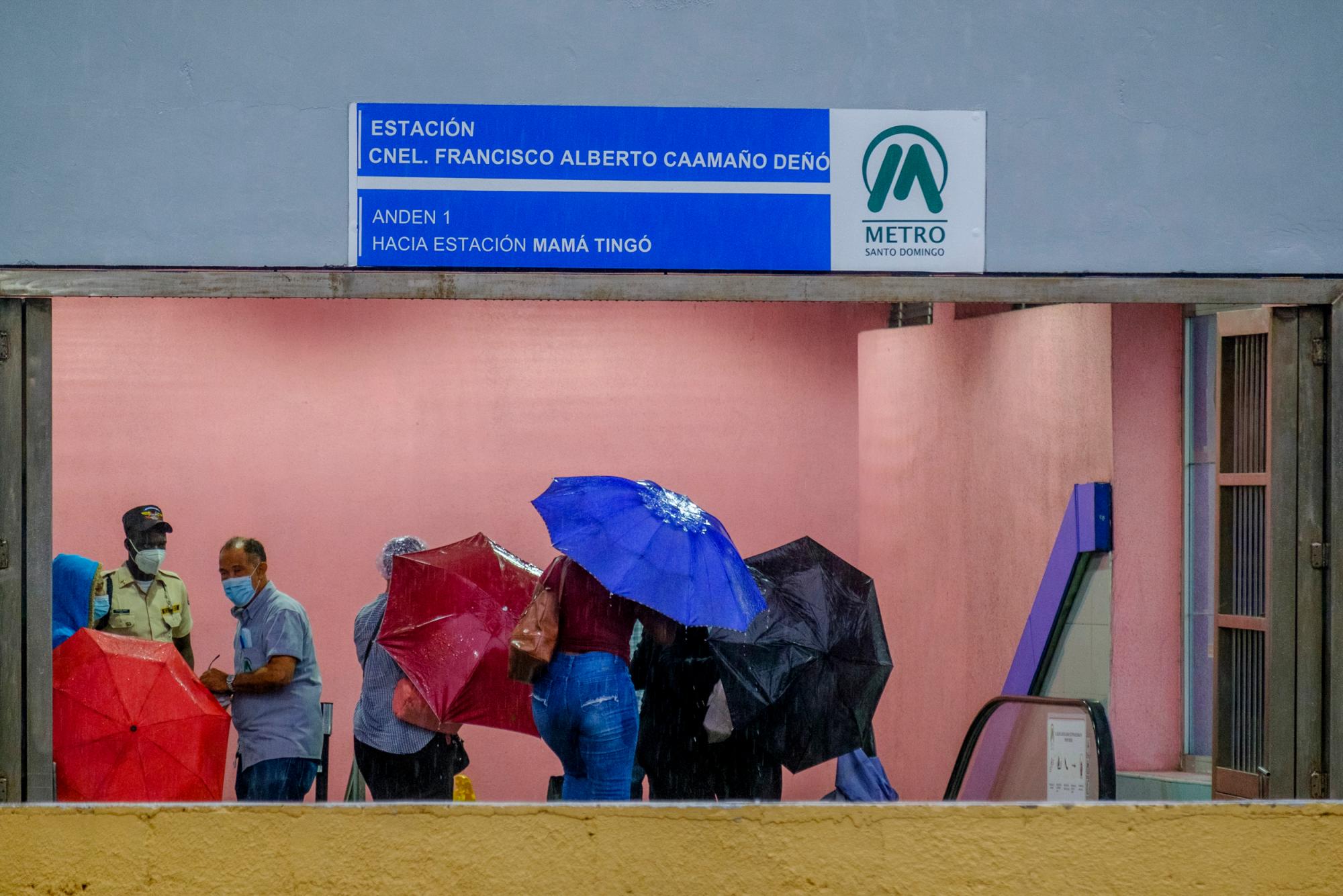 Varias mujeres sacuden sus paraguas al llegar al entrar de la estación Coronel Francisco Alberto Caamaño Deñó, del Metro de Santo Domingo 