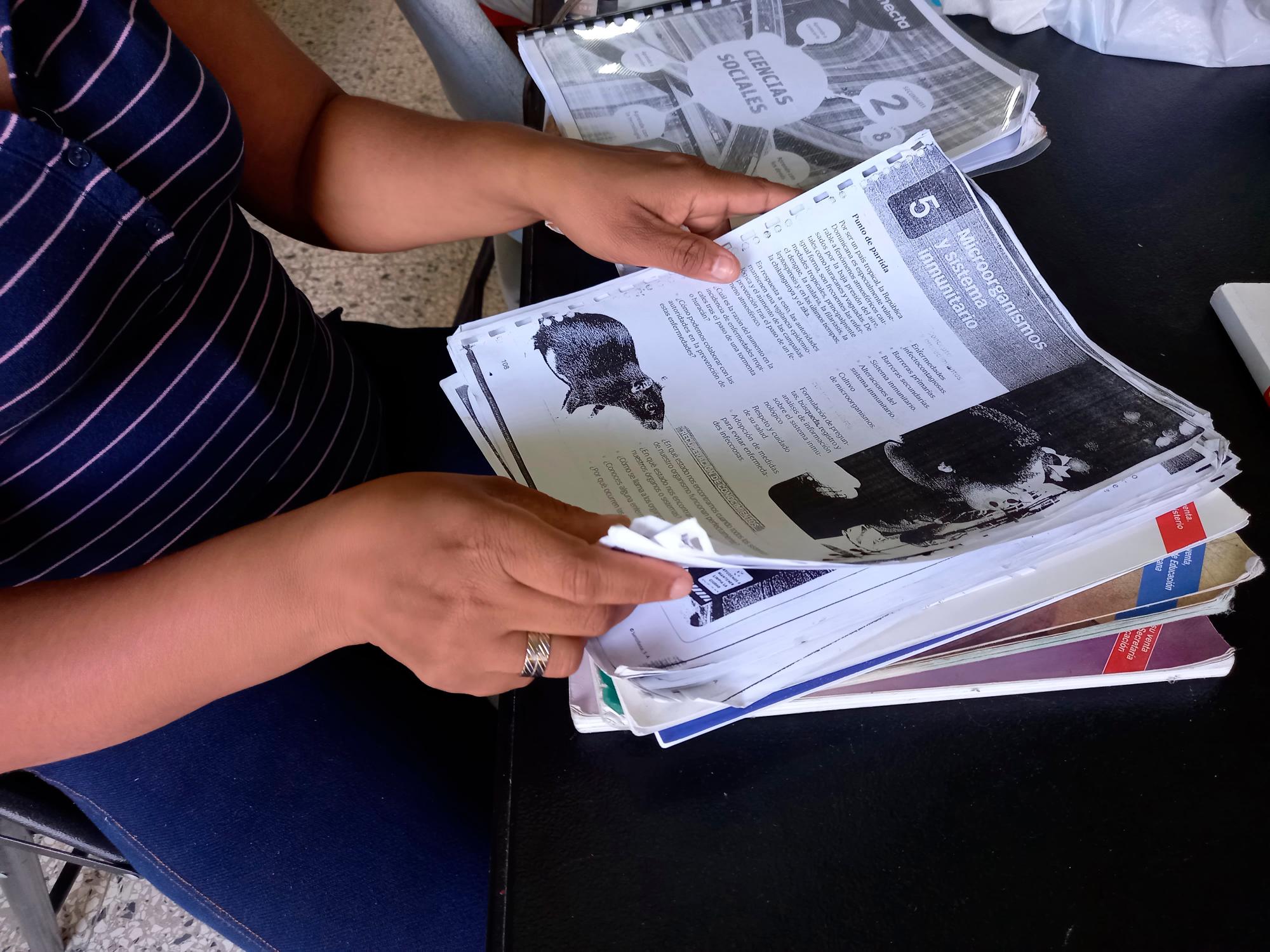 La profesora Kelly Gil muestra las fotocopias que sacó de un libro editado para el sector privado y que usó para preparar una clase.