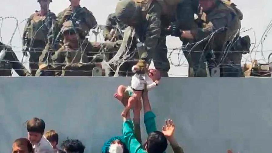 Un bebé afgano es entregado por encima de un muro en Kabul a soldados de EEUU