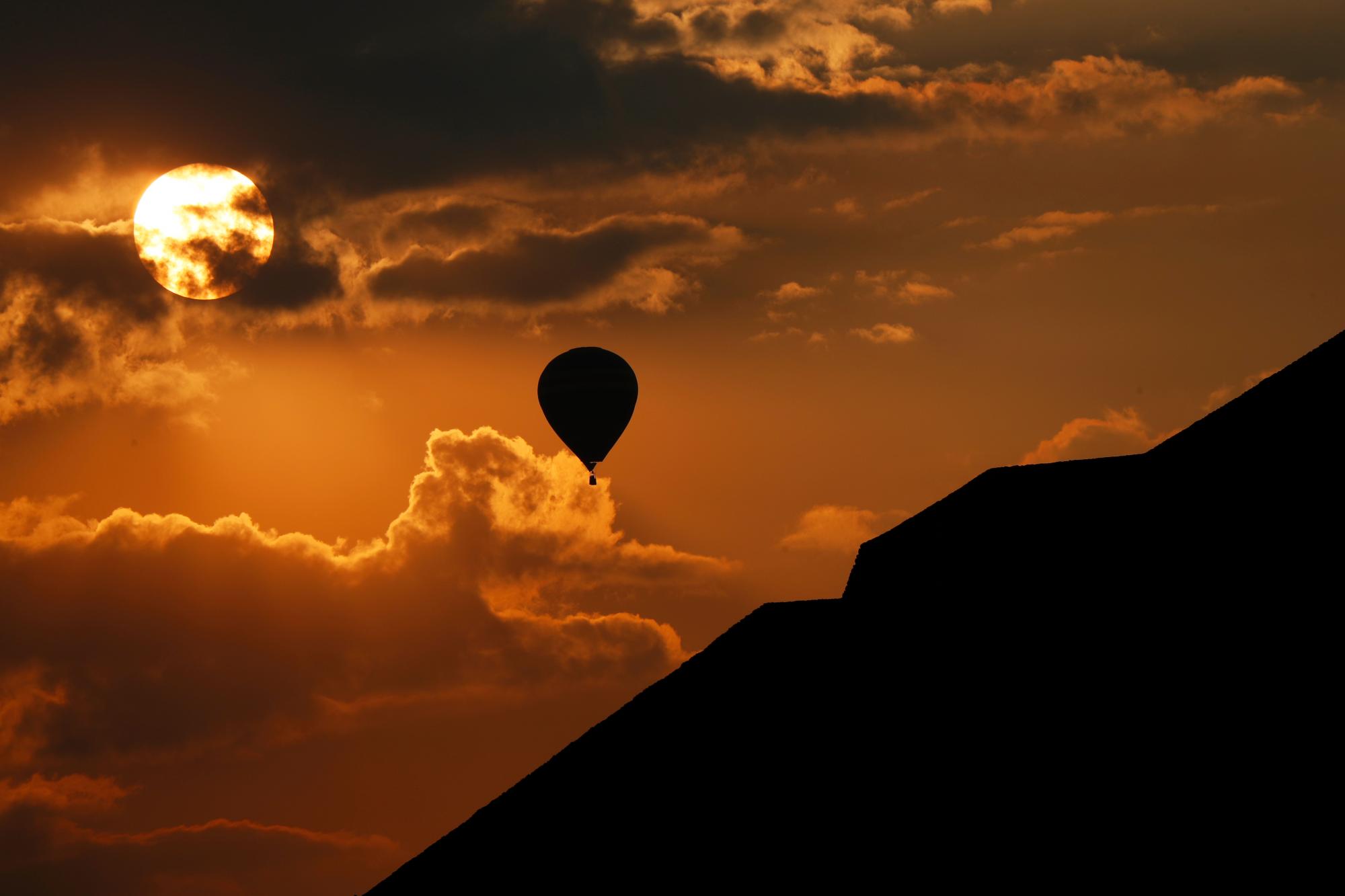 En esta imagen del jueves 21 de marzo de 2019, un globo aerostático vuela cerca de la Pirámide del Sol al amanecer en Teotihuacán, México, durante el equinoccio de primavera.