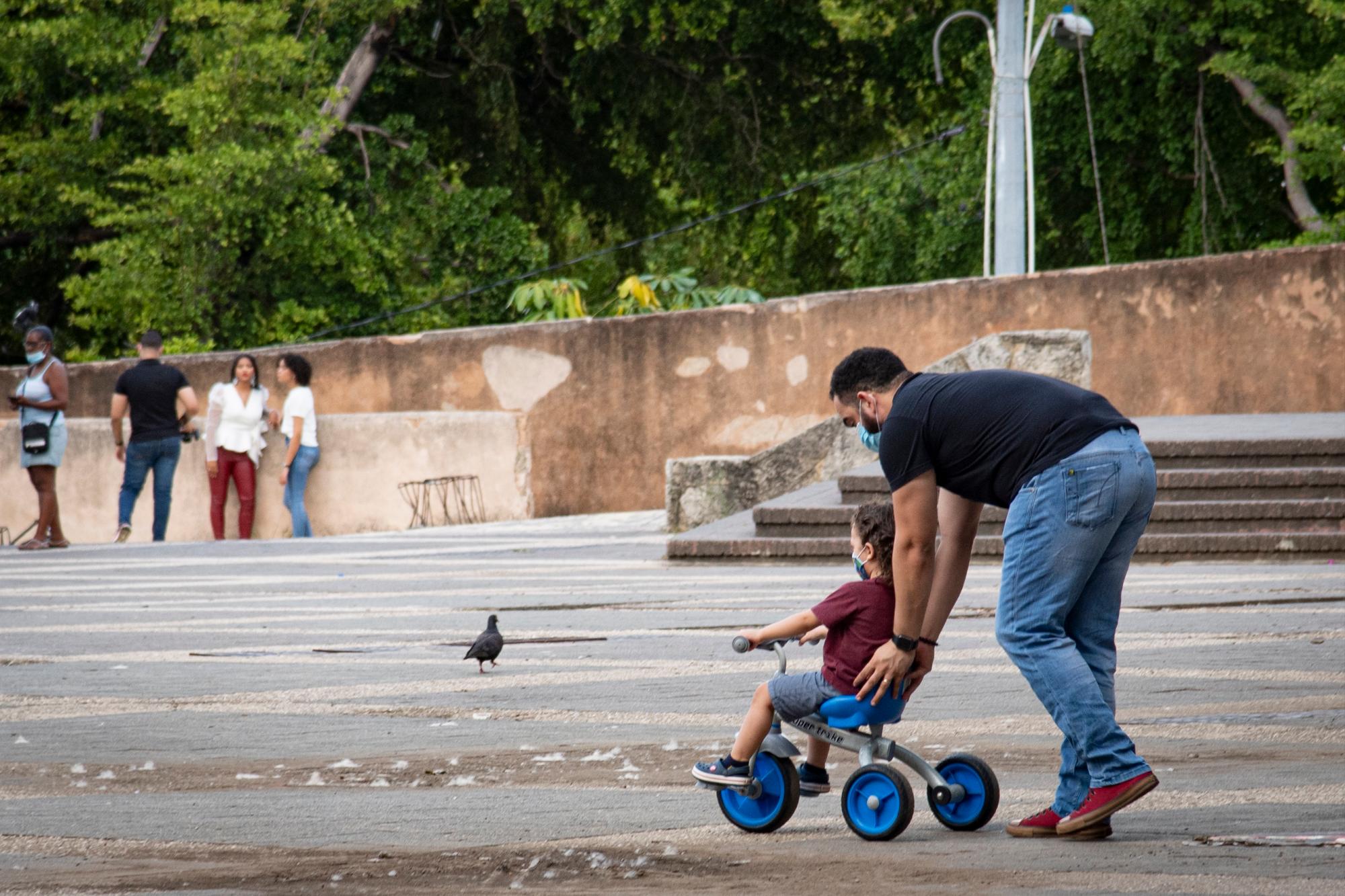 Padre ayuda a su hijo en su velocípedo.