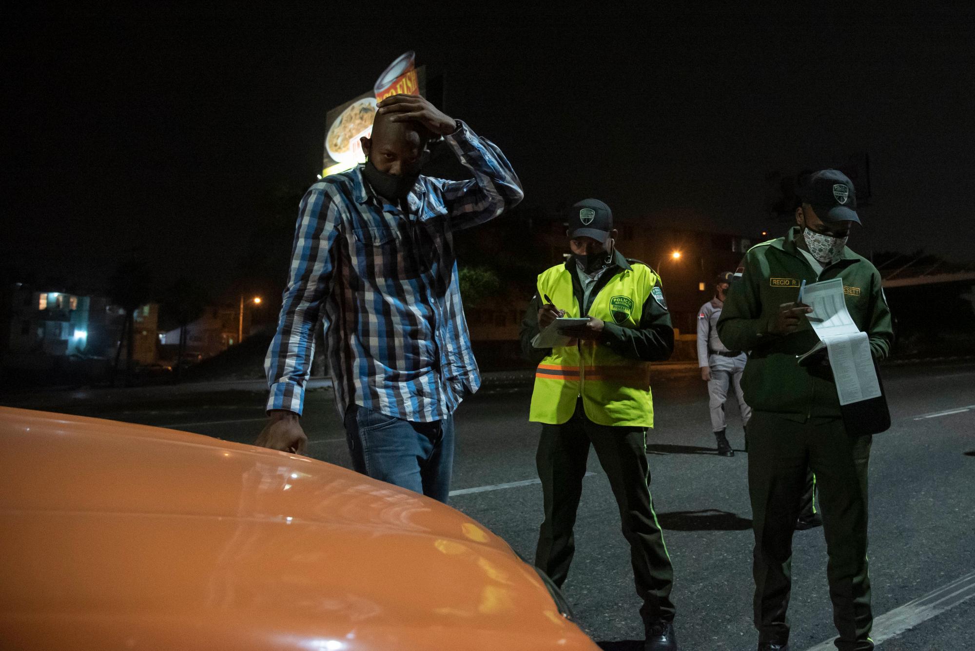 Un hombre se coloca una mano en la cabeza cuando le indican que está detenido y su vehículo va al centro de retención vehicular.