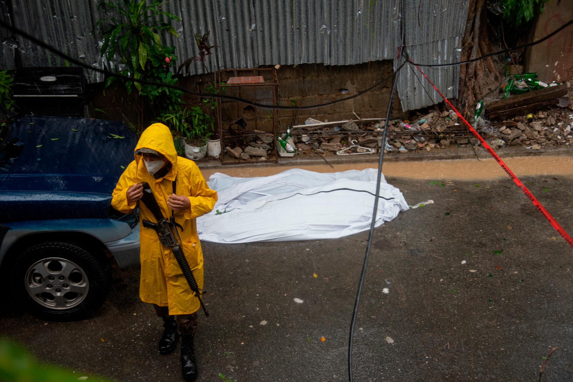 Un militar custodia el área donde se encontraron  los cuerpo de una  señora y su hijo de unos 8 años, quienes murieron aplastados cuando parte de una pared se desplomó en la calle La Palmera, del sector del mismo nombre, en Santo Domingo Oeste.