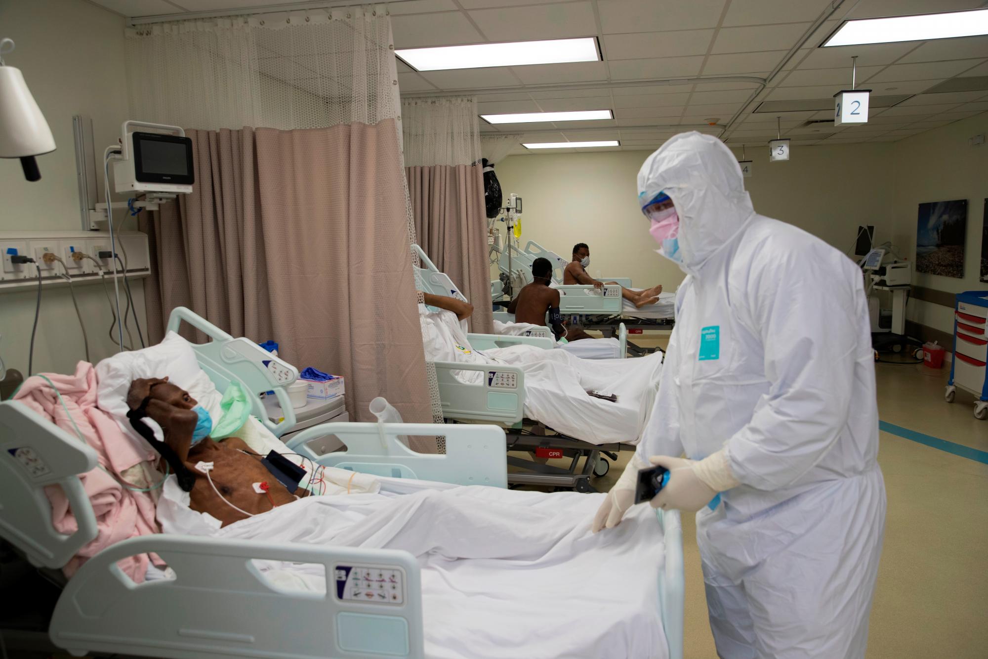 El doctor Darvy Taveras, emergenciólogo e intensivista, habla con un paciente en el área de Cuidados Intensivos de la Unidad COVID-19 del Centro de Oftalmología y Trasplante Cardio-Neuro (Cecanot) en Santo Domingo, República Dominicana, 15 de mayo de 2020. Durante todo el día, 63 médicos, 120 enfermeras y 35 empleados de servicios generales atienden a unos 40 pacientes en el centro de salud. EFE / Orlando Barria