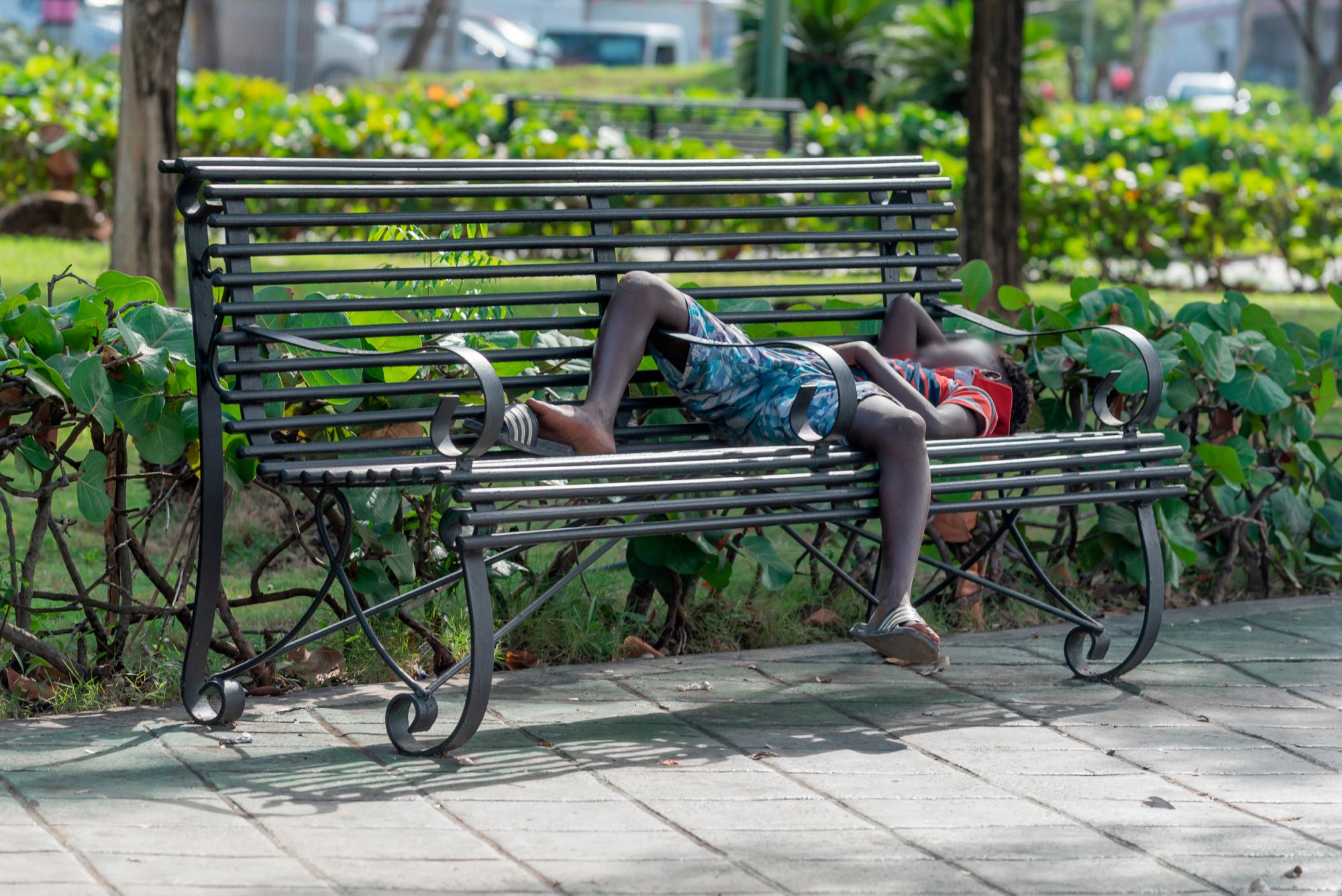 Un niño de alrededor 11 años de edad duerme relajadamente en un banco del Parque Zooberto.