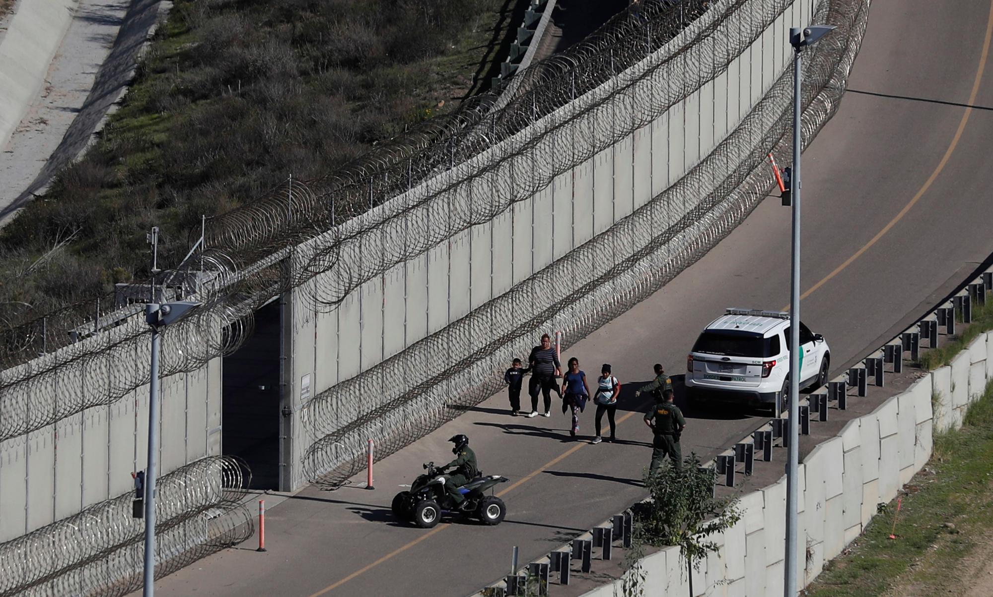 Los agentes de la Patrulla Fronteriza de EEUU detienen a los solicitantes de asilo hondureños después de cruzar el muro fronterizo de los EEUU hacia San Diego, California, desde Tijuana, México.