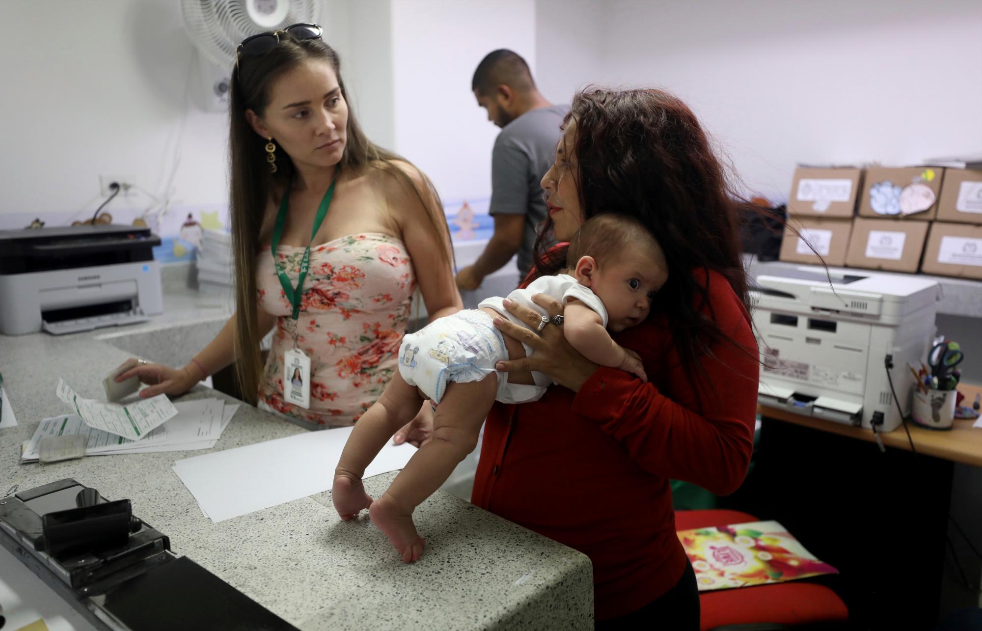 Arelys Pulido, a la derecha, sostiene a su hija de dos meses Zuleidys Antonella Primera mientras hace los trámites para el certificado de nacimiento del bebé en el hospital Erazmo Meoz en Cúcuta, Colombia, en la frontera con Venezuela, el jueves 2 de mayo de 2019. 