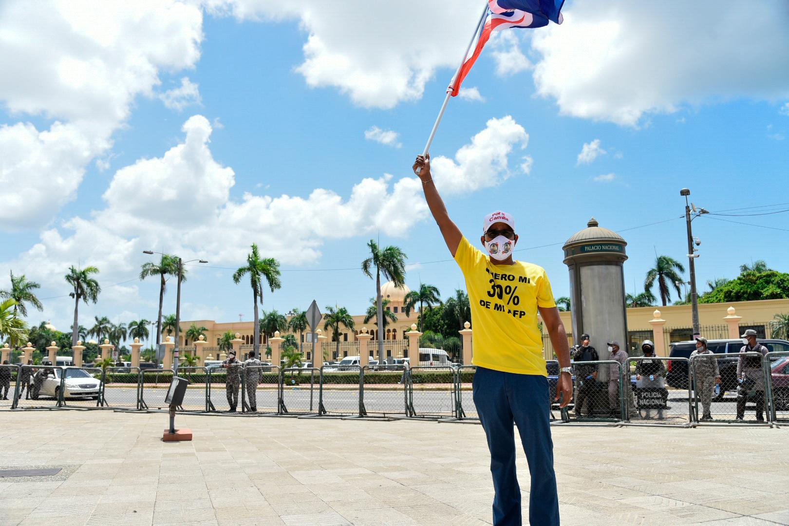Protestante frene al Palacio Presidencial y Con la bandera Dominica en alto.