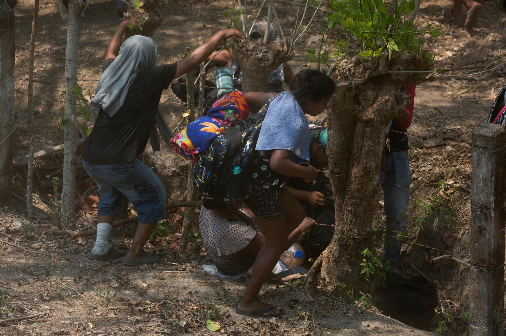 Los migrantes centroamericanos que viajaban por el sur de México hacia Estados Unidos, con temor, recordaron su frenético escape de la policía el día anterior, cruzan por debajo de cercas de alambre de púas después de pasar la noche en el bosque.
