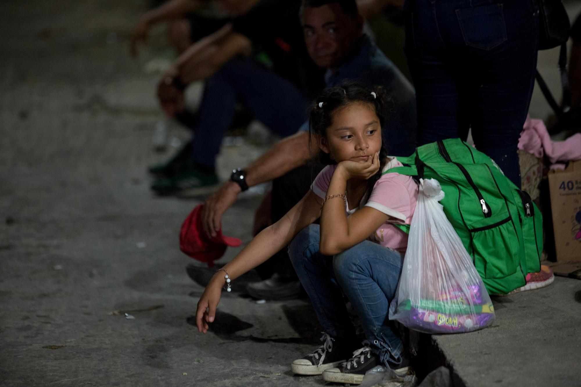 Los migrantes centroamericanos sentados en la acera listos para correr, después de que los agentes de inmigración mexicanos se acercaran a la estación de tren en Arriaga, estado de Chiapas, México, el jueves 25 de abril de 2019.
