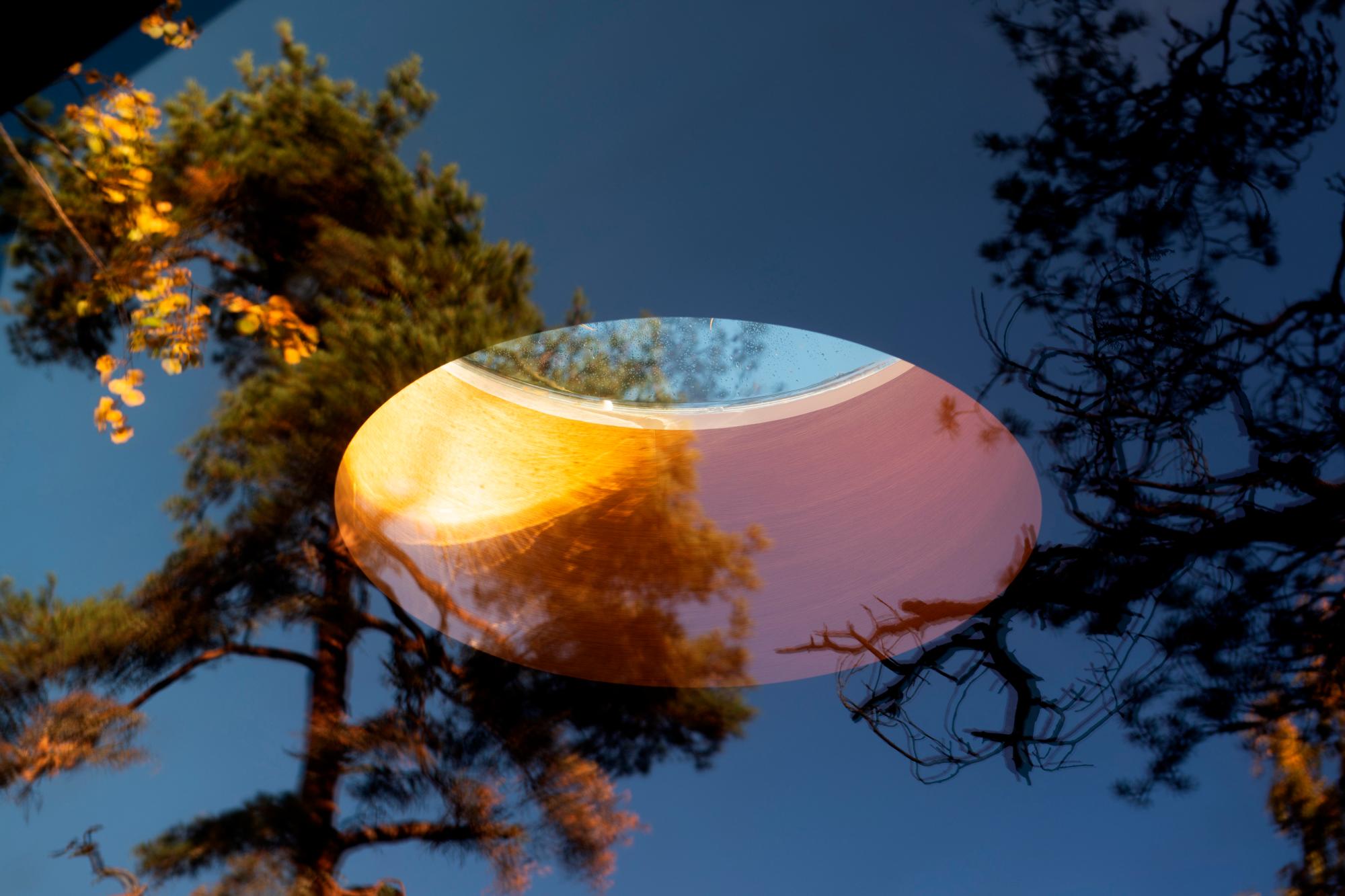 Una especie de ojo de buey se asoma en el techo de la cabaña que está incrustada en el bosque de Oslo.