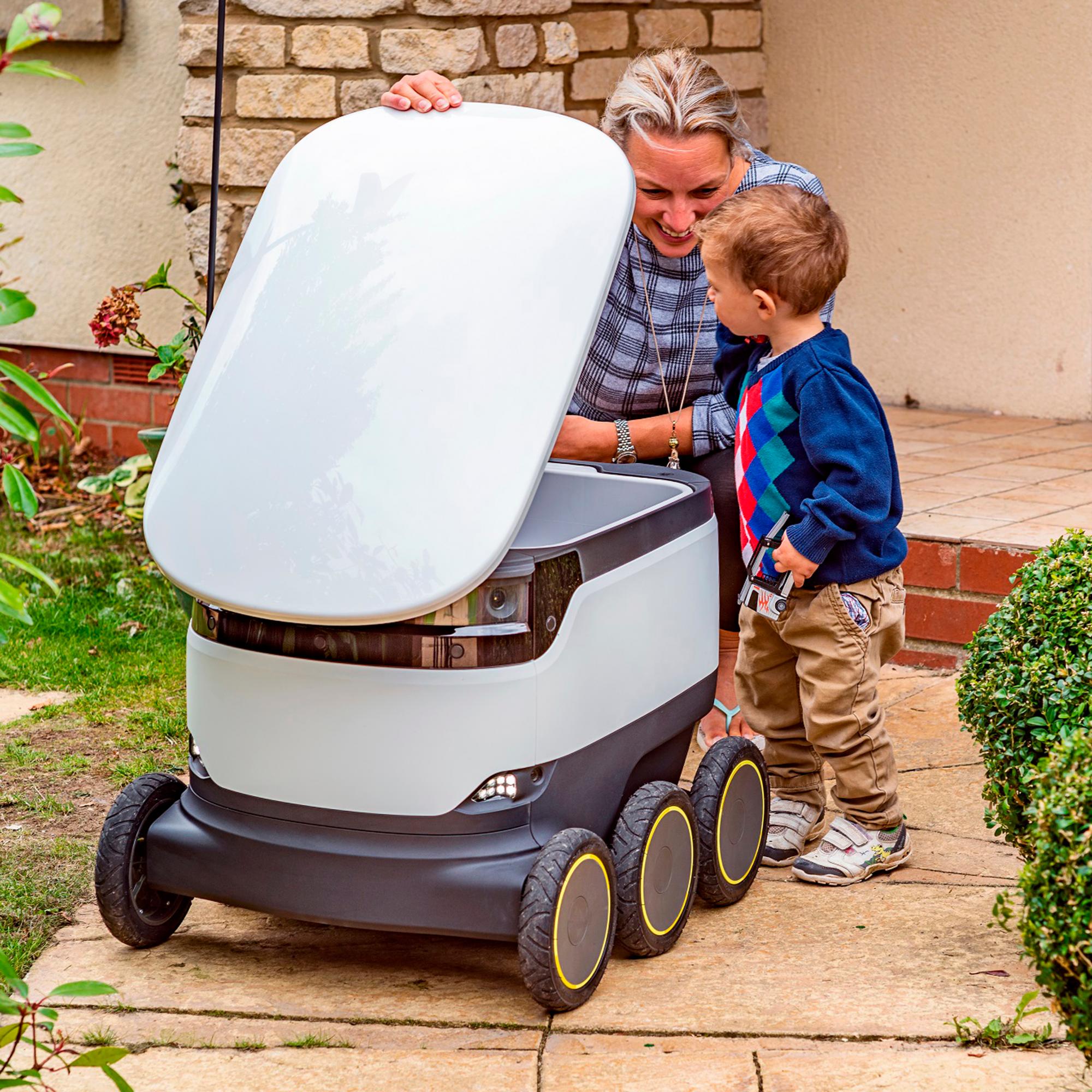 Una madre recoge el pedido de un robot con su hijo al lado.