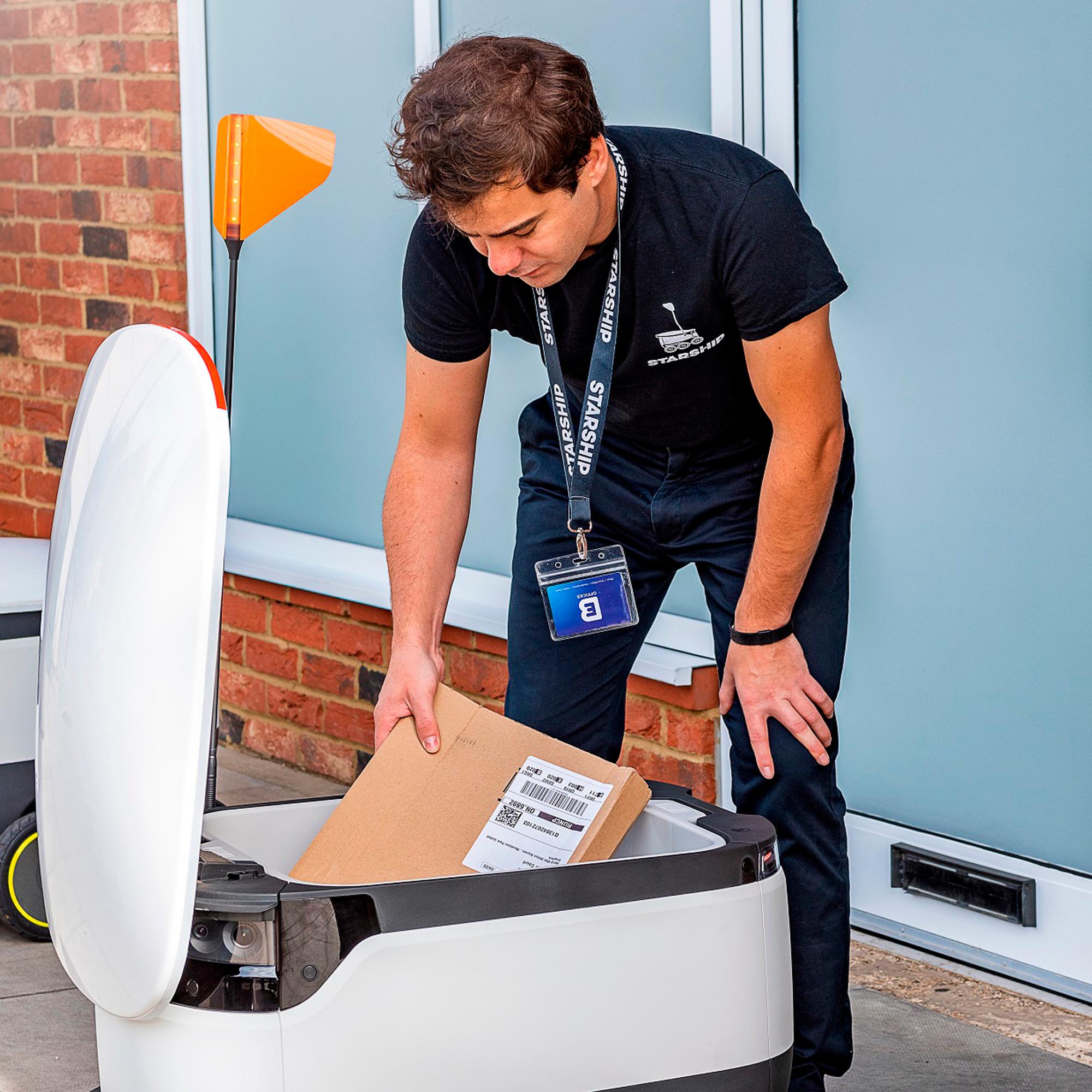 Un operario de la firma tecnológica carga al robot con un paquete para su reparto inmediato.