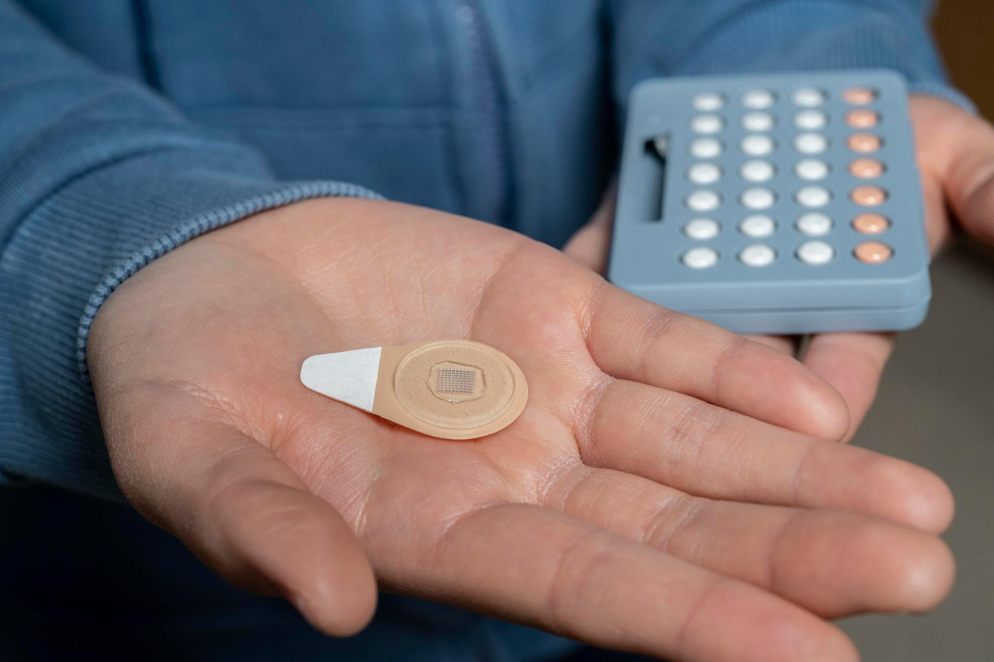 Un parche experimental de micro agujas junto a un paquete de blister de píldoras anticonceptivas.