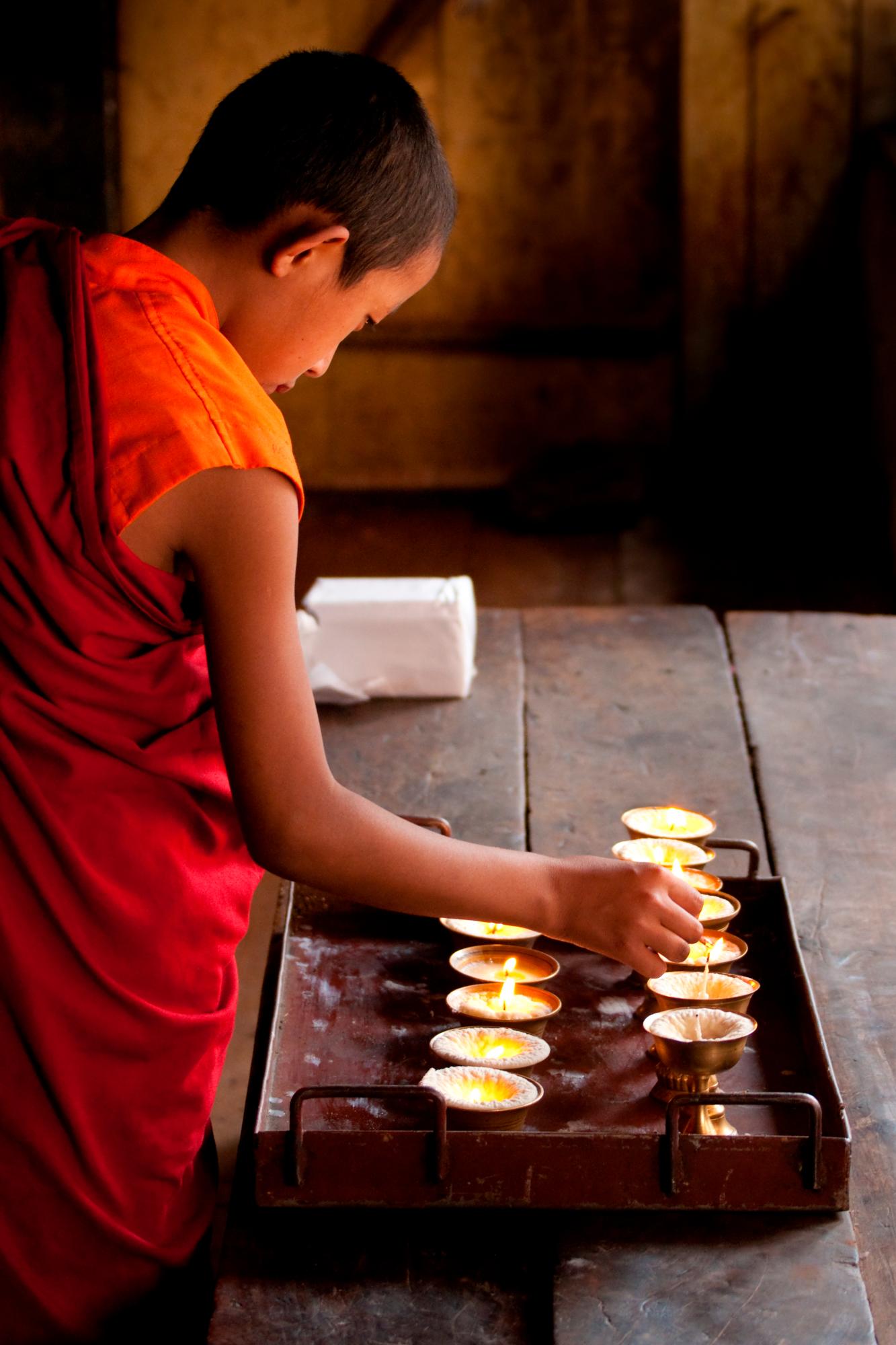 Un joven estudiante budista poniendo una ofrenda en un templo de Bután.