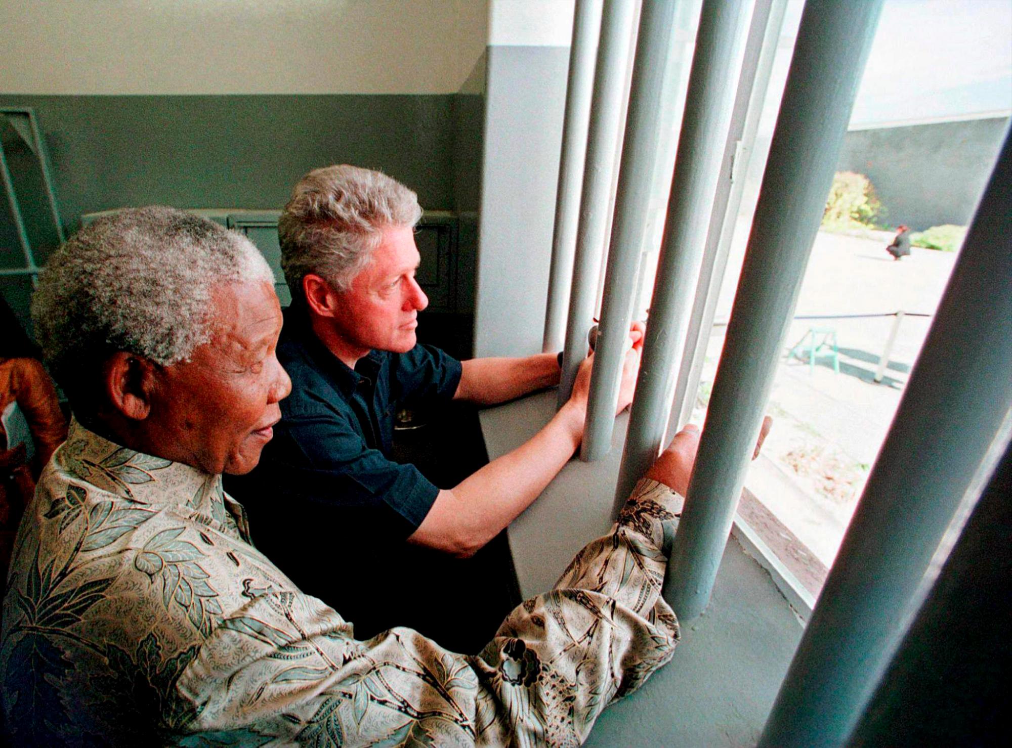 ROBBEN ISLAND (SUDÁFRICA), 4/2/2010.- El premio Nobel de la paz y líder sudafricano Nelson Mandela (izquierda) y el entonces presidente de Estados Unidos Bill Clinton (derecha) se asoman a la ventana de la celda donde Mandela estuvo 18 de sus 27 años como preso político en Robben Island, Sudáfrica, el 27 de marzo de 1998. El próximo jueves 11 de febrero se cumplen 20 años de la liberación de Nelson Mandela como prisionero político en su país. El 11 de febrero de 1990 Mandela fue liberado de la prisión de Ciudad del Cabo y cuatro años después fue elegido presidente hasta 1999 en las primeras elecciones en las que los negros obtuvieron el derecho al voto en Sudáfrica. 