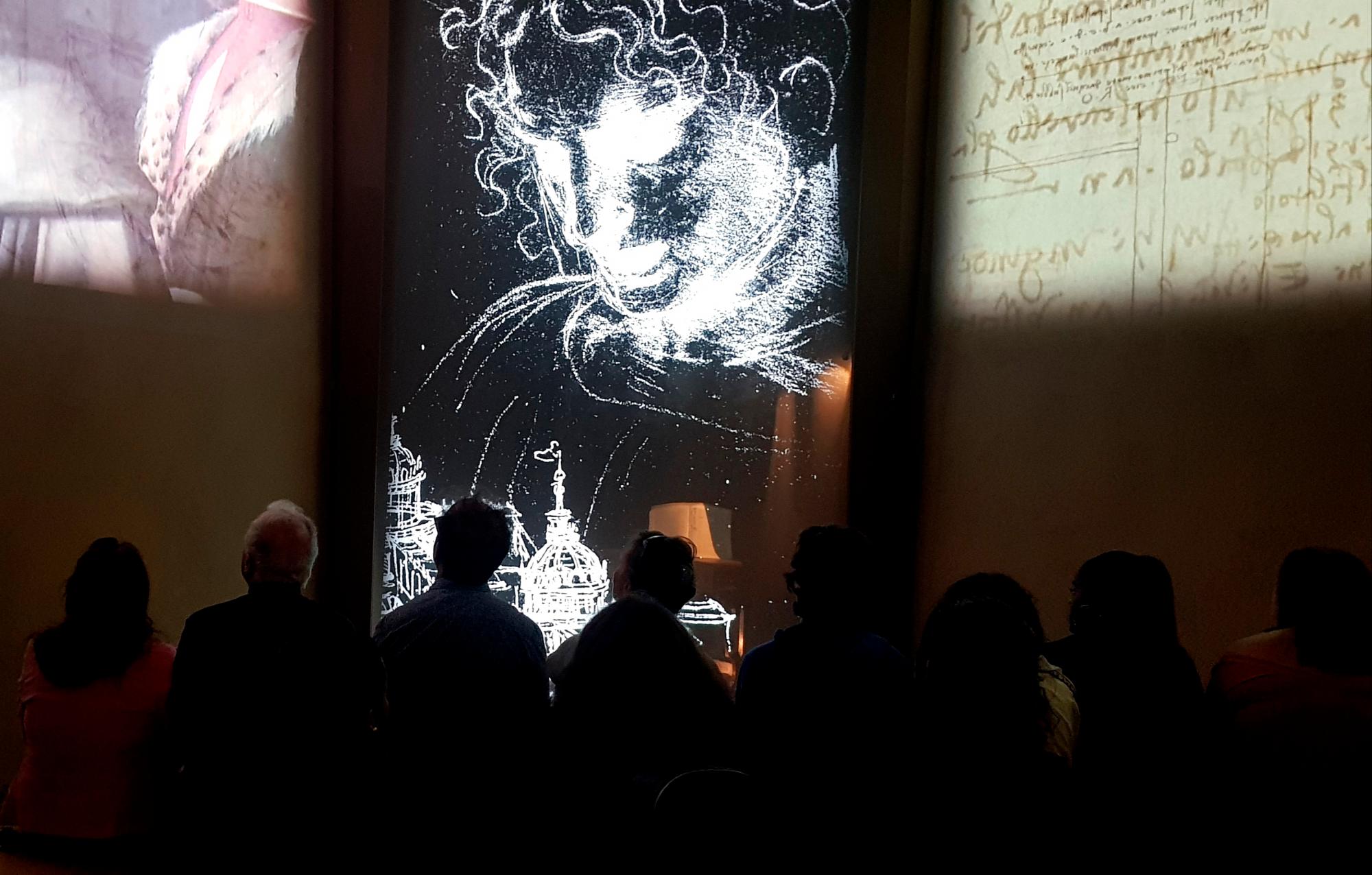 Un grupo de personas atienden a un vídeo ilustrativo sobre la vida de Leonardo Da Vinci en la casa natal del genio. 