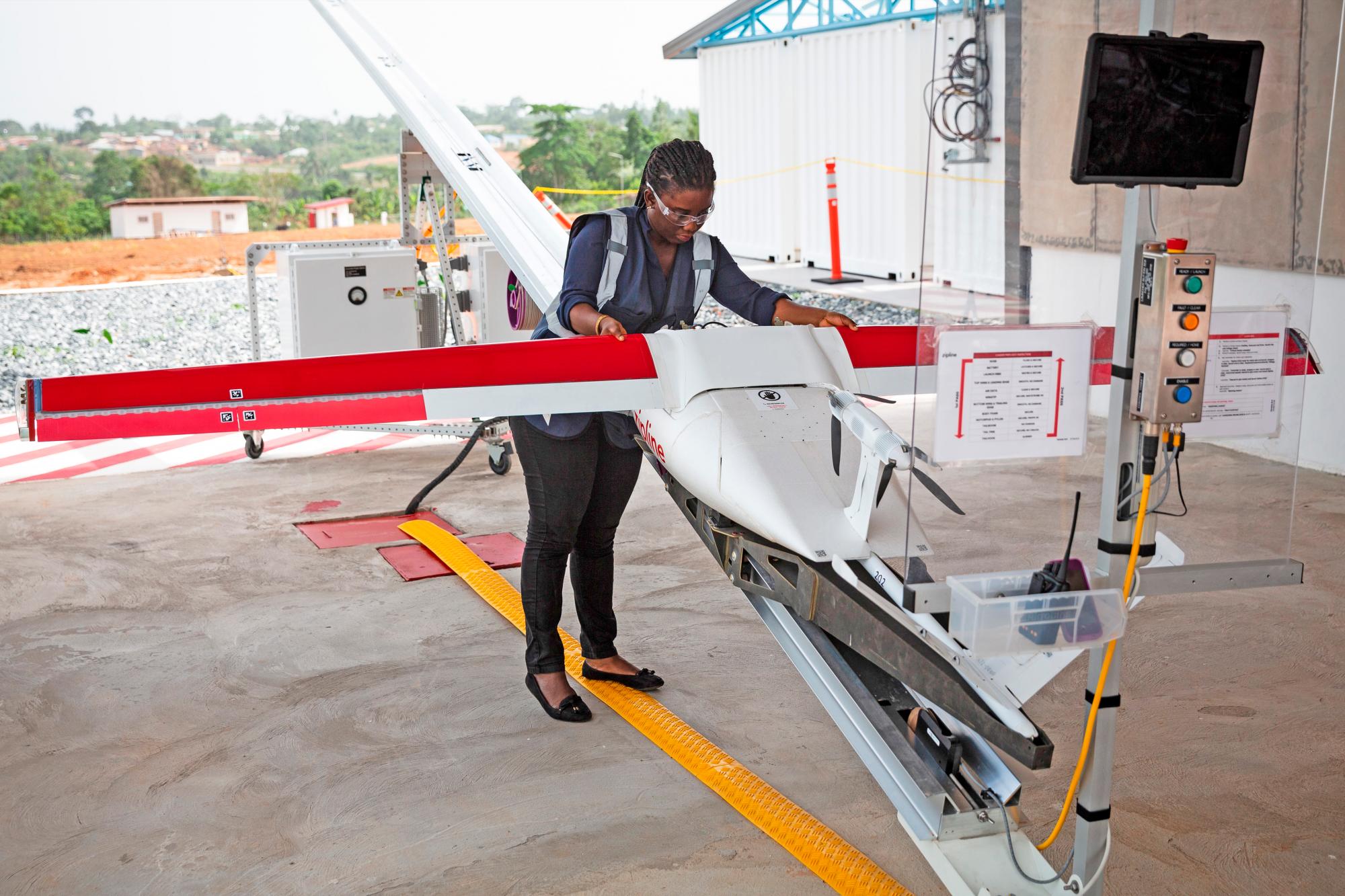 Una operaria sanitaria ghanesa preparando un dron para incorporar un envío médico a una zona de difícil acceso. 