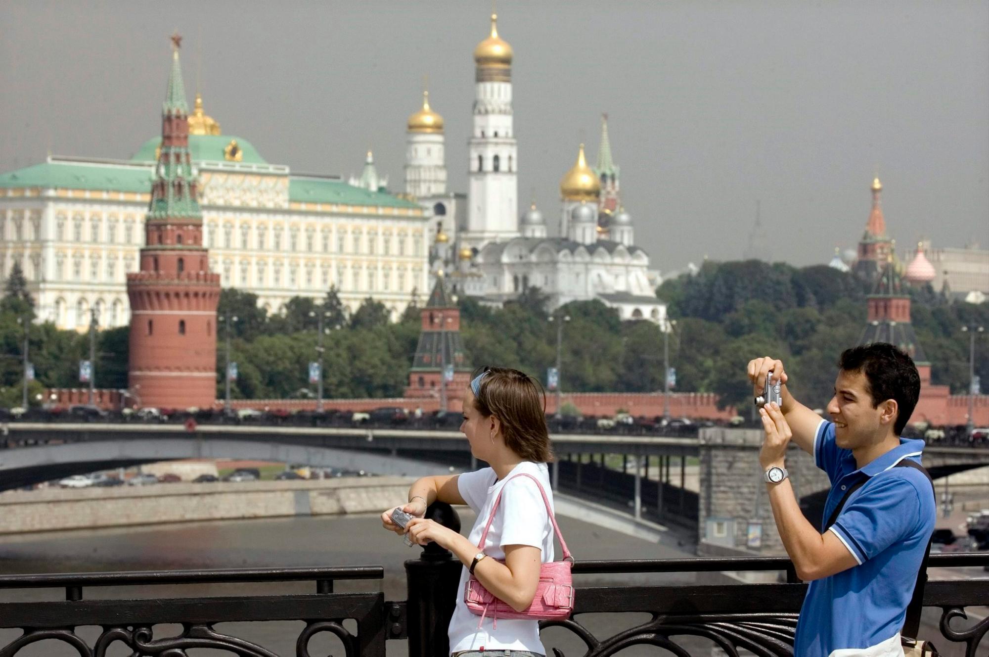 Unos turistas extranjeros toman una foto mientras cruzan el río Moscú. 