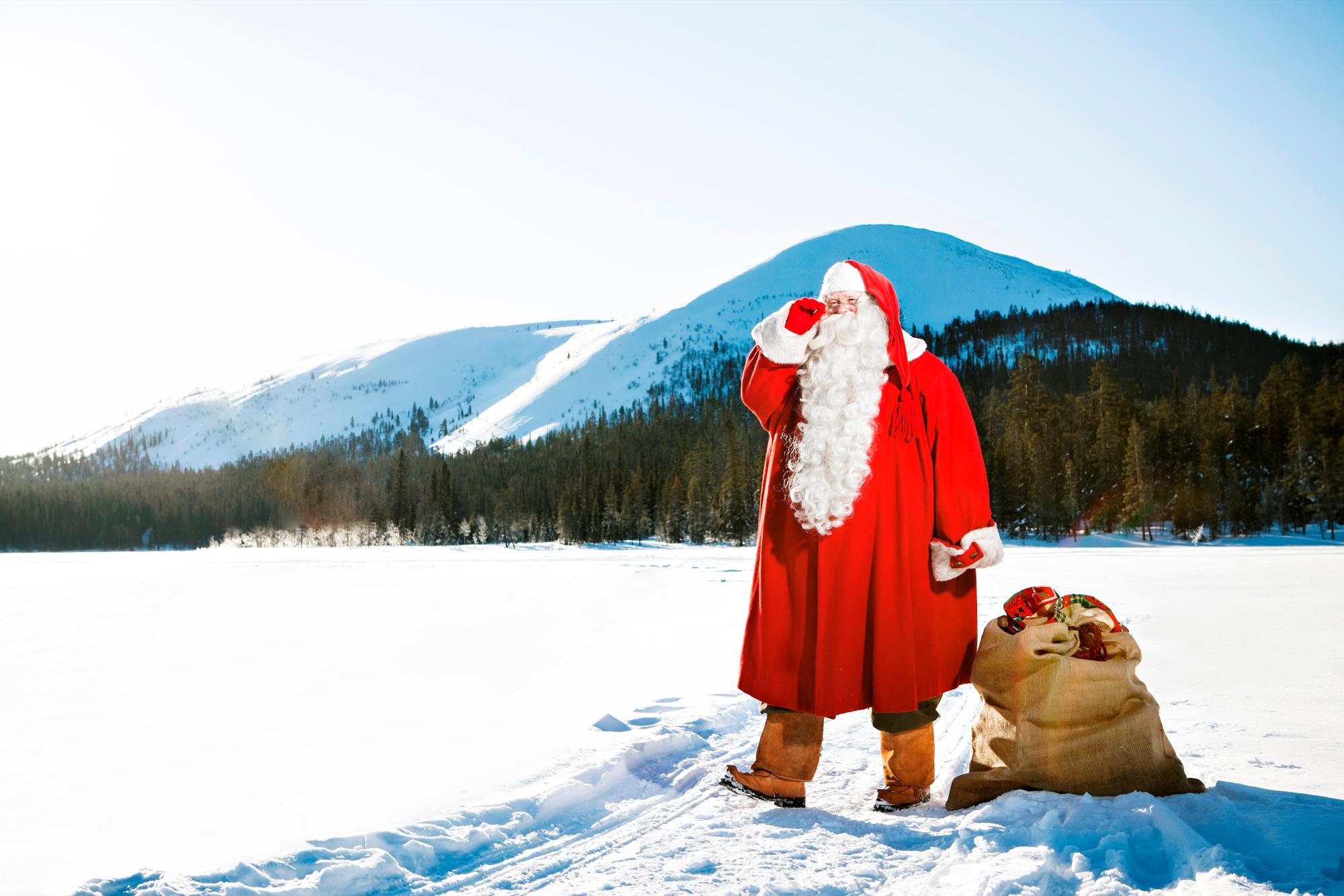 Santa, con uno de los sacos repleto de regalos, se encamina hacia su vehículo para cargarlo.