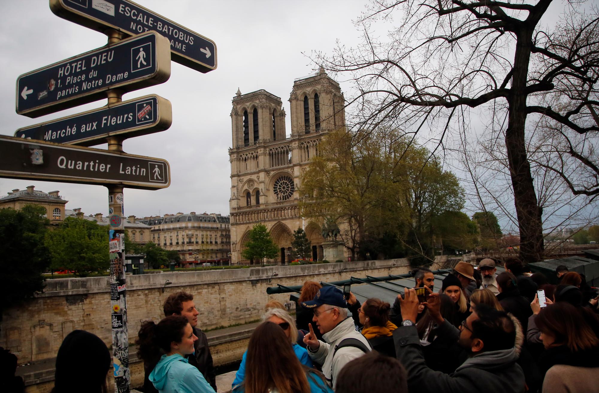 La gente mira la Catedral de Notre Dame en París, el martes 16 de abril de 2019. Los bomberos declararon éxito el martes en una batalla de más de 12 horas para extinguir un infierno que envuelve la icónica Catedral de Notre Dame de París.