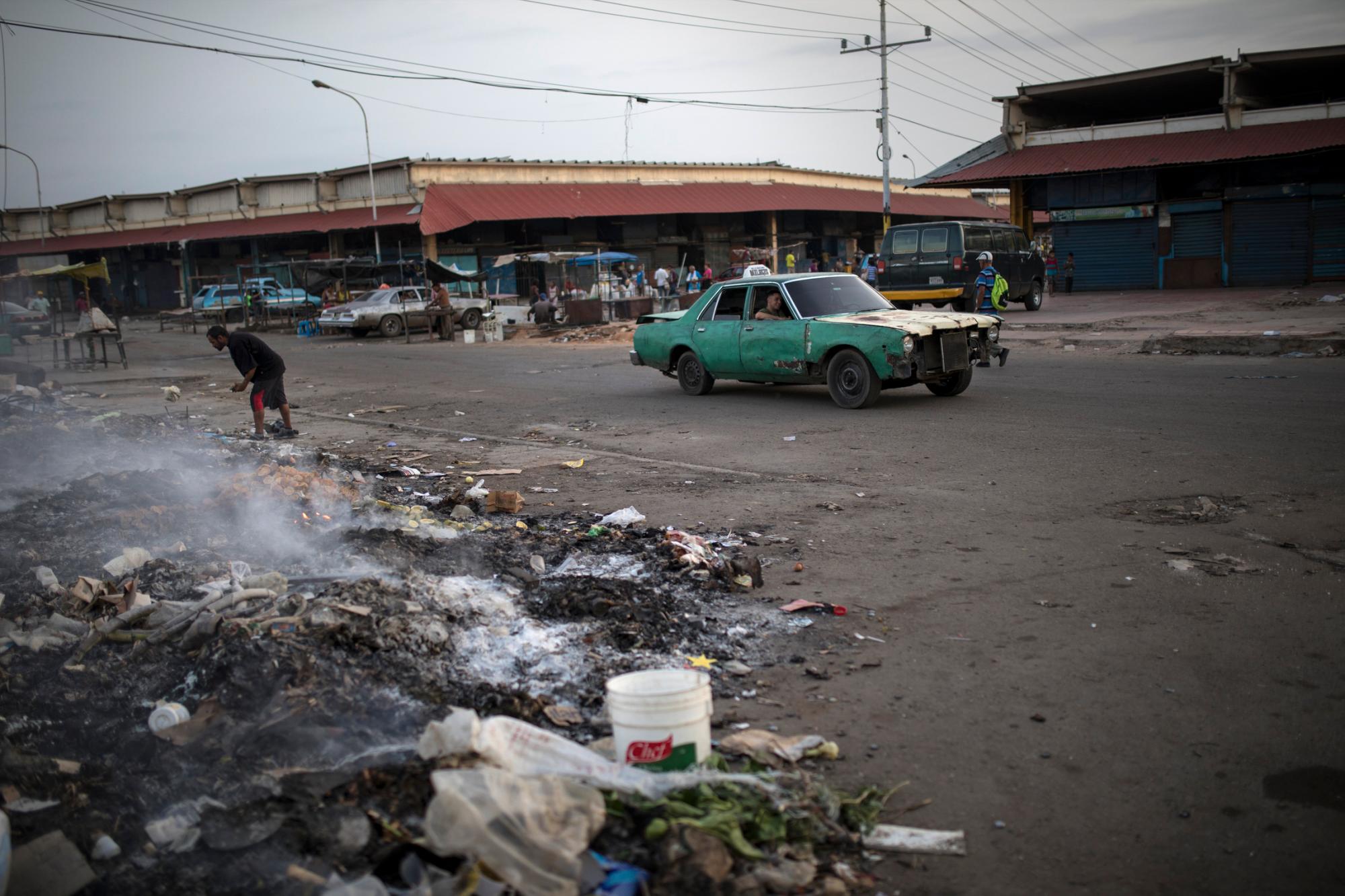En la imagen, tomada el 14 de mayo de 2019, un hombre rebusca entre la basura en el exterior de un mercado en Maracaibo, Venezuela. A medida que el enfrentamiento político se prolonga, también lo hace la vida en Maracaibo. Algunos revuelven en la basura y buscan comida.