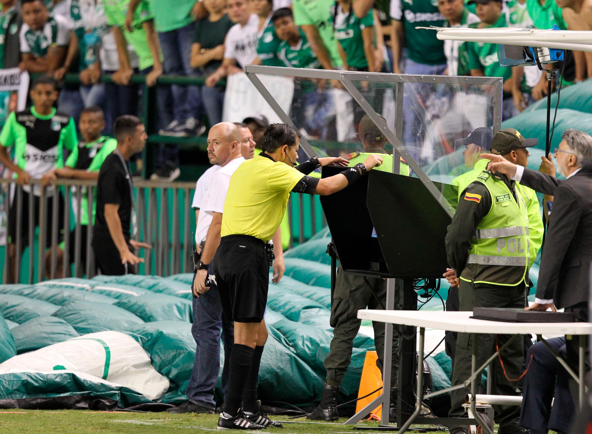 El árbitro peruano Víctor Carrillo (c) revisa una acción con el Árbitro Asistente de Vídeo (VAR) durante un partido de los cuartos de final de la Copa Sudamericana.