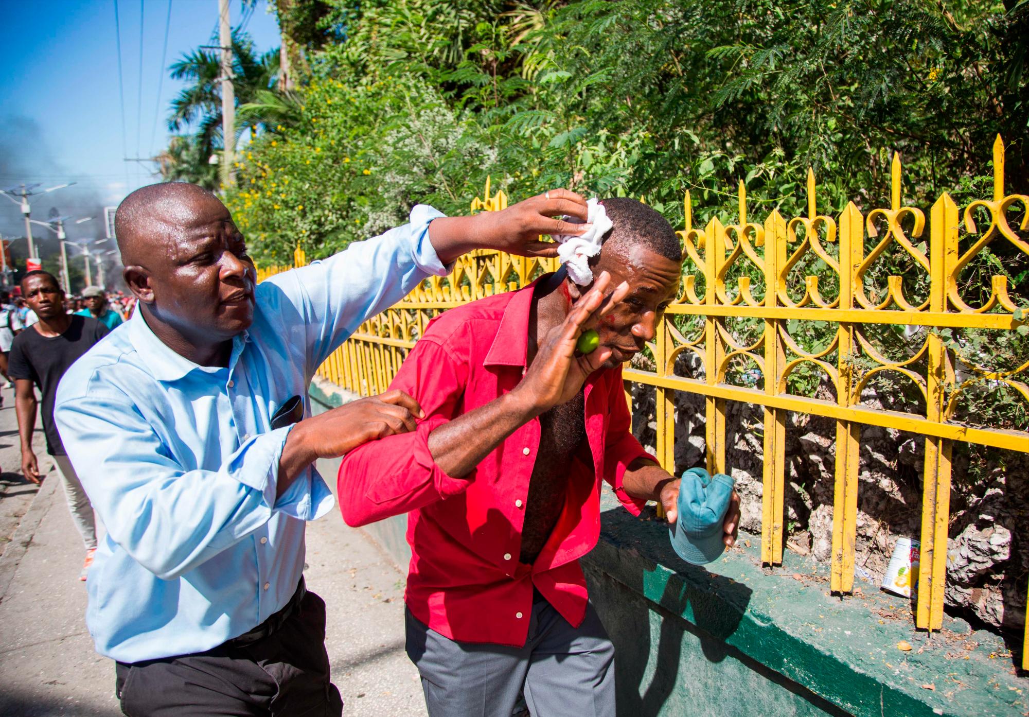 Un hombre atiende a un herido durante una protesta, en Puerto Príncipe (Haití) hoy, domingo 18 de noviembre de 2018. Miles de haitianos salieron hoy a las calles para participar en una nueva protesta nacional contra la corrupción y la impunidad, que ha dejado al menos dos muertos y varios heridos.