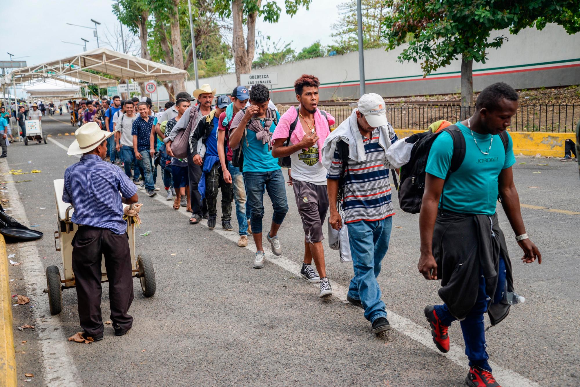  Migrantes hondureños que han decidido acogerse a la tarjeta humanitaria, esperan este lunes para ingresar de manera legal a territorio mexicano, en el puente que cruza el rio Suchiate, en Ciudad Hidalgo (México). 