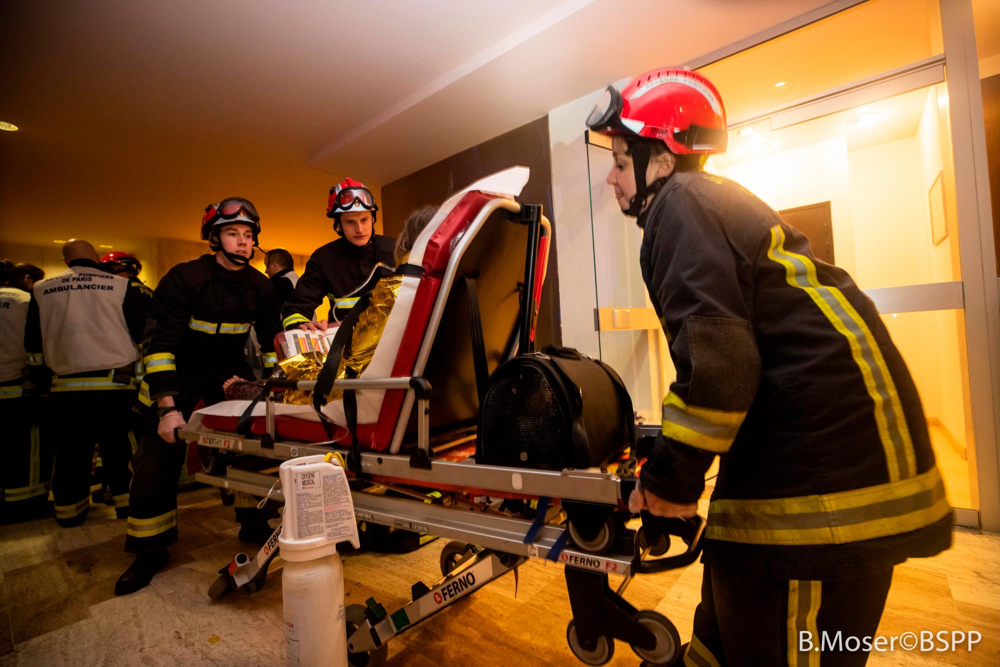 Los bomberos evacúan a un herido durante el incendio desatado este martes en un edificio de ocho plantas.