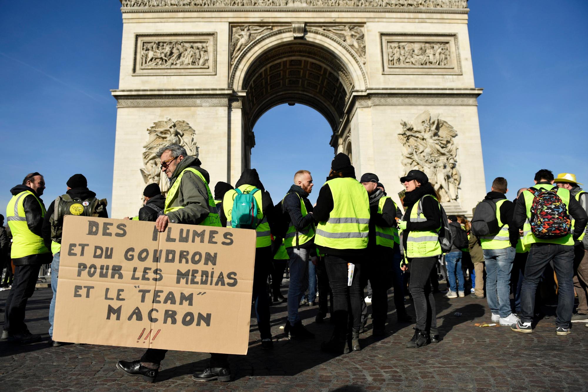 París (Francia), 16/02/2019.- Manifestantes con un cartel que dice: ‘Caminando y amontonando a los medios de comunicación y al equipo Macron’ del movimiento ‘Gilets Jaunes’ (Chalecos amarillos) se reúnen en la avenida de los Campos Elíseos, cerca de Arc de Tiomphe durante la manifestación del ‘Acto XIV’ (la 14a protesta nacional consecutiva en un sábado) en París, Francia, el 16 de febrero de 2019. El llamado ‘Gilets Jaunes’ es un movimiento de protesta de base con partidarios de una amplia gama de espectro político, que originalmente comenzó con una protesta en todo el país a fines de 2018 contra los altos precios del combustible.
