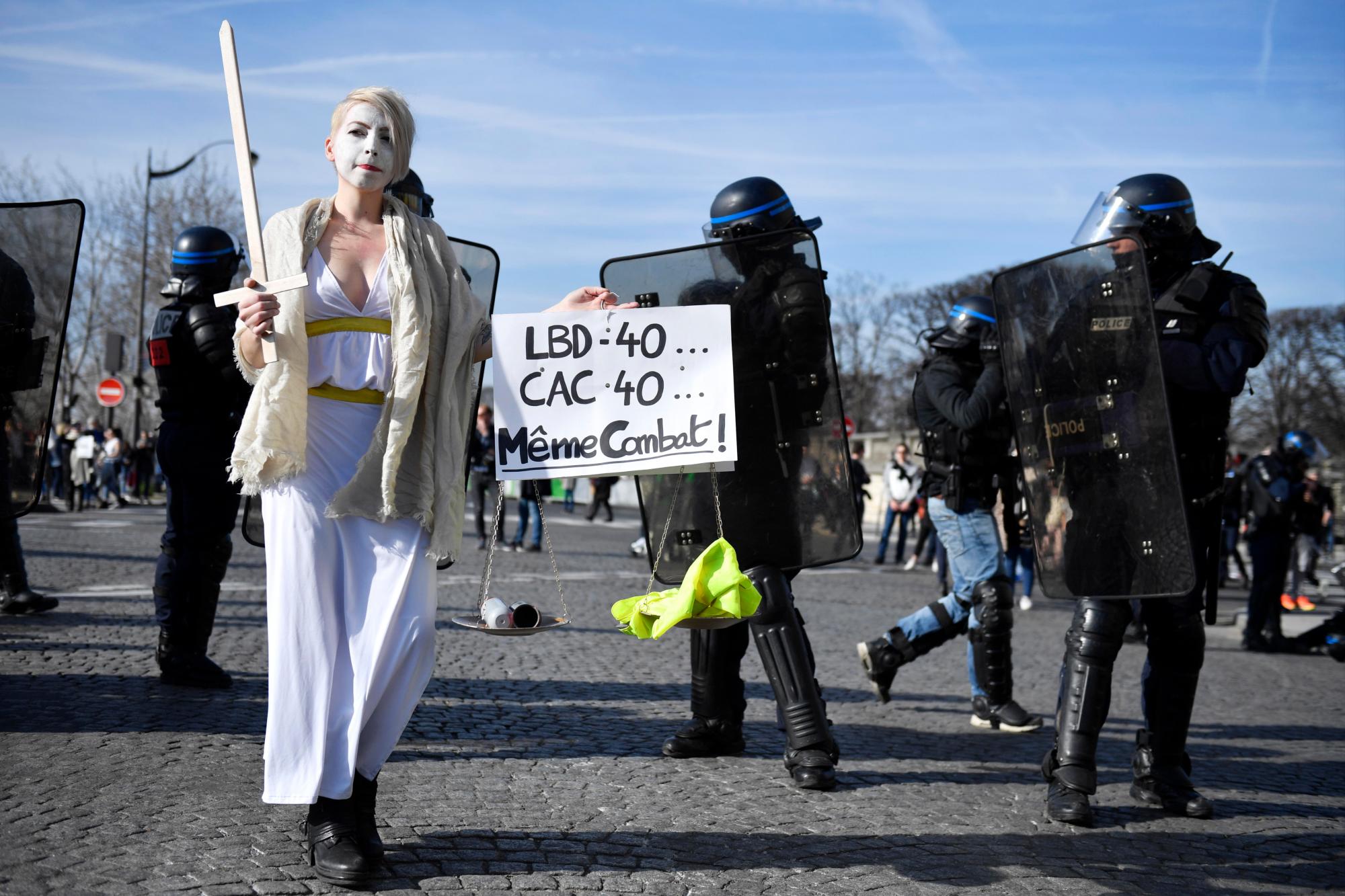 París (Francia), 16/02/2019.- Un manifestante del movimiento ‘Gilets Jaunes’ (chalecos amarillos) sostiene un cartel ‘LBD-40 ... CAC-40 ... La misma lucha’ durante el ‘Acto XIV’ manifestación (la 14a protesta nacional consecutiva en un sábado) en París, Francia, 16 de febrero de 2019. El llamado ‘Gilets Jaunes’ es un movimiento de protesta popular con partidarios de un amplio espectro del espectro político, que originalmente comenzó con la protesta a través de La nación a finales de 2018 contra los altos precios del combustible.