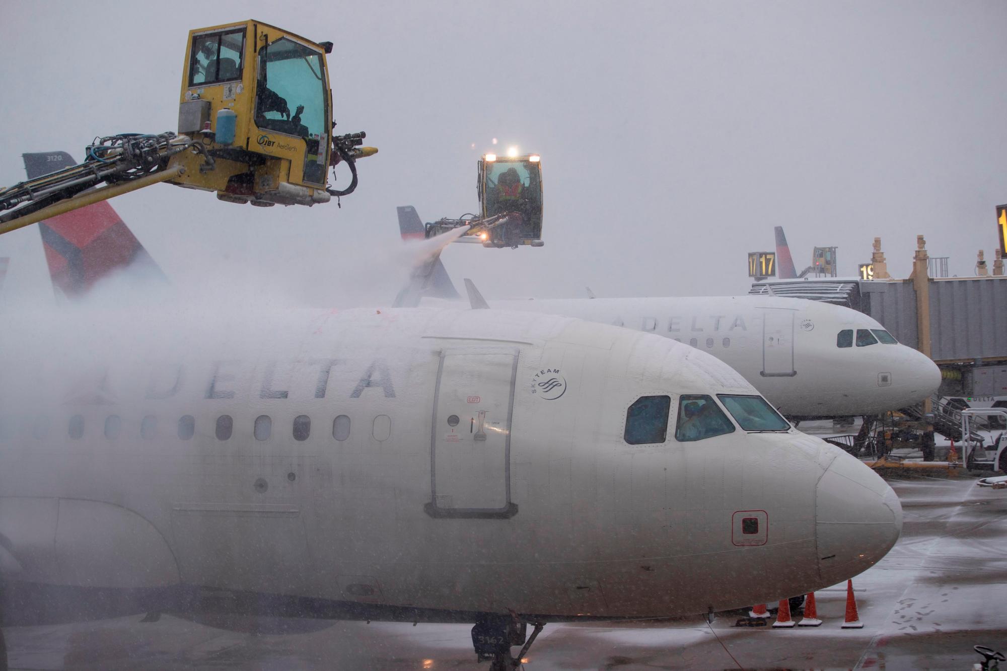 Varios trabajadores del aeropuerto asisten al despegue de un avión en Arlington, Virginia (Estados Unidos), este miércoles, durante una jornada de tormenta de nieve y bajas temperaturas. 
